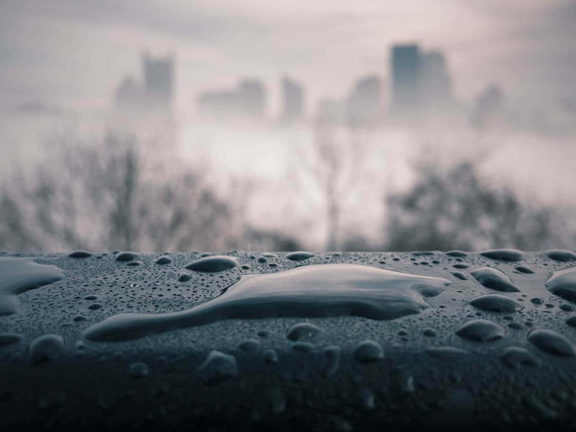 特寫雨滴落在表面上，背景是模糊的城市景觀。