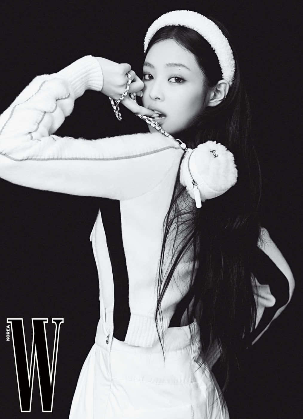 BLACKPINK Jennie Kim為《W》雜誌拍攝黑白寫真 壁紙 — 一位時尚的女性以單色造型在黑色背景前自信地擺姿勢，戴著白色頭帶和服裝，配以鏈條飾品。