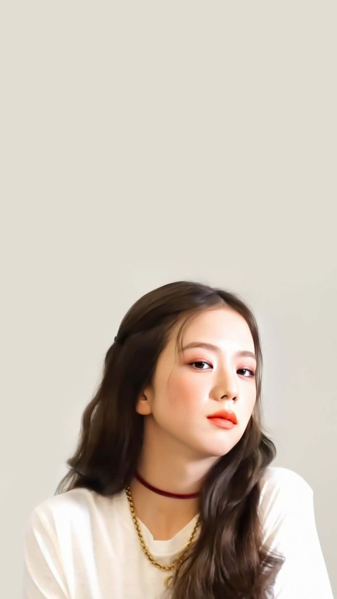 BLACKPINK 成員 Jisoo 無限閃耀 壁紙 — 一位年輕女性，長長的波浪棕色頭髮，在純淨淺米色背景上柔和地向上凝視。