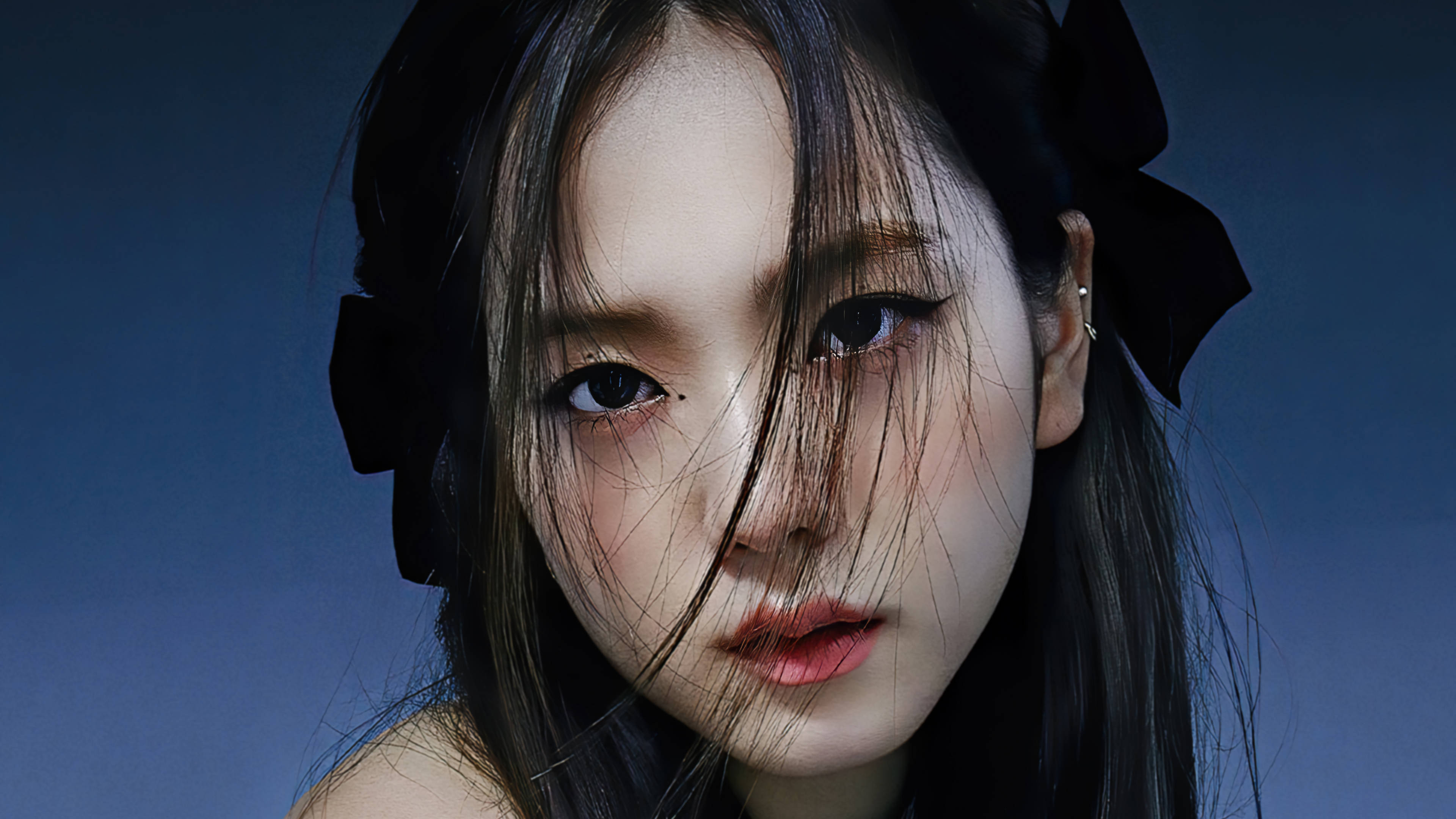 BLACKPINK JISOO 特寫 壁紙 — 一位年輕女性的特寫肖像，深色頭髮，戴著大黑色蝴蝶結，背景為冷藍色。