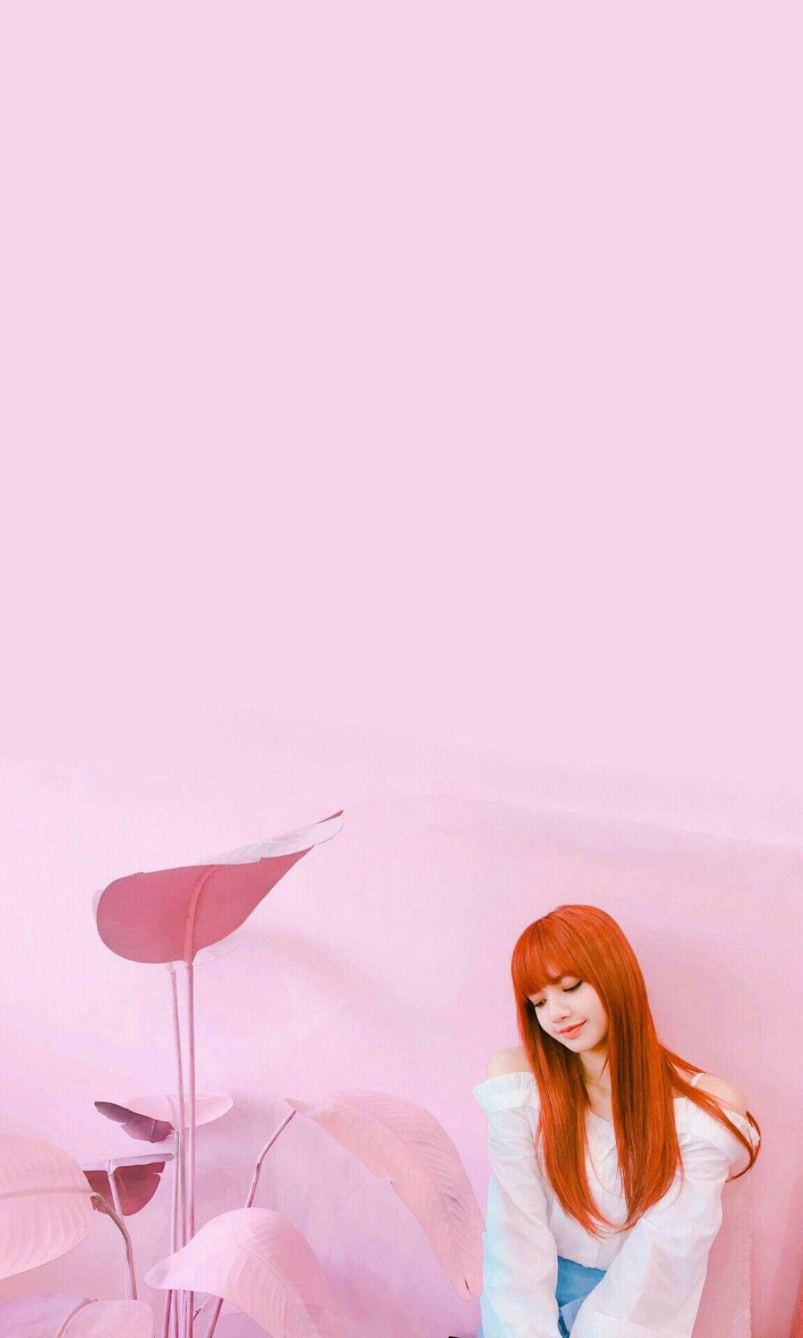 BLACKPINK LISA 粉色房間 壁紙 — 一位擁有鮮豔紅髮的年輕女性，在柔和的粉紅色背景前，安詳地坐在超大的粉紅色植物旁邊。