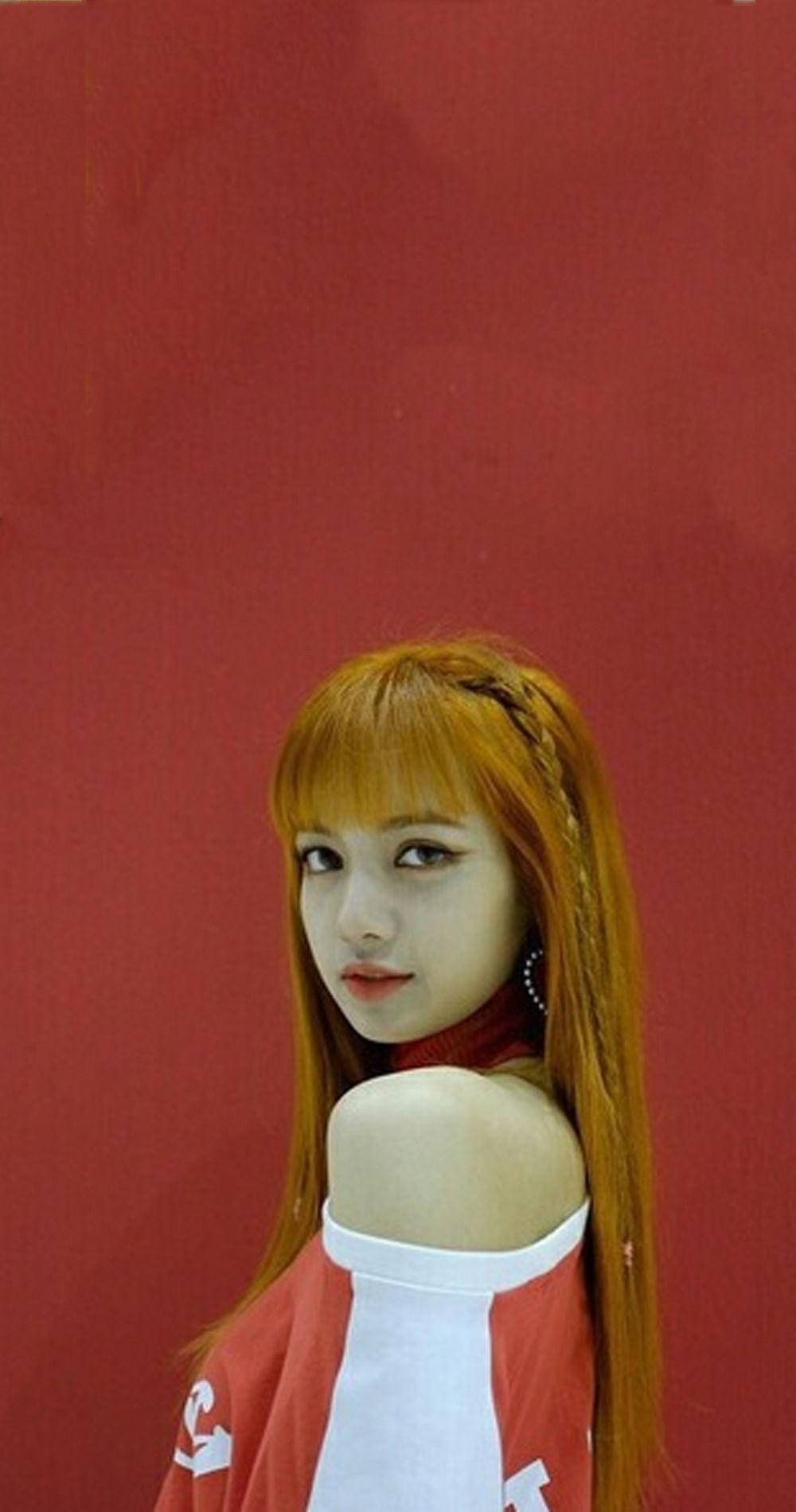 BLACKPINK LISA 懸肩裝造型 壁紙 — 一位擁有鮮豔橙色頭髮和紅色背景的年輕女性，穿著紅白露肩上衣擺姿勢。