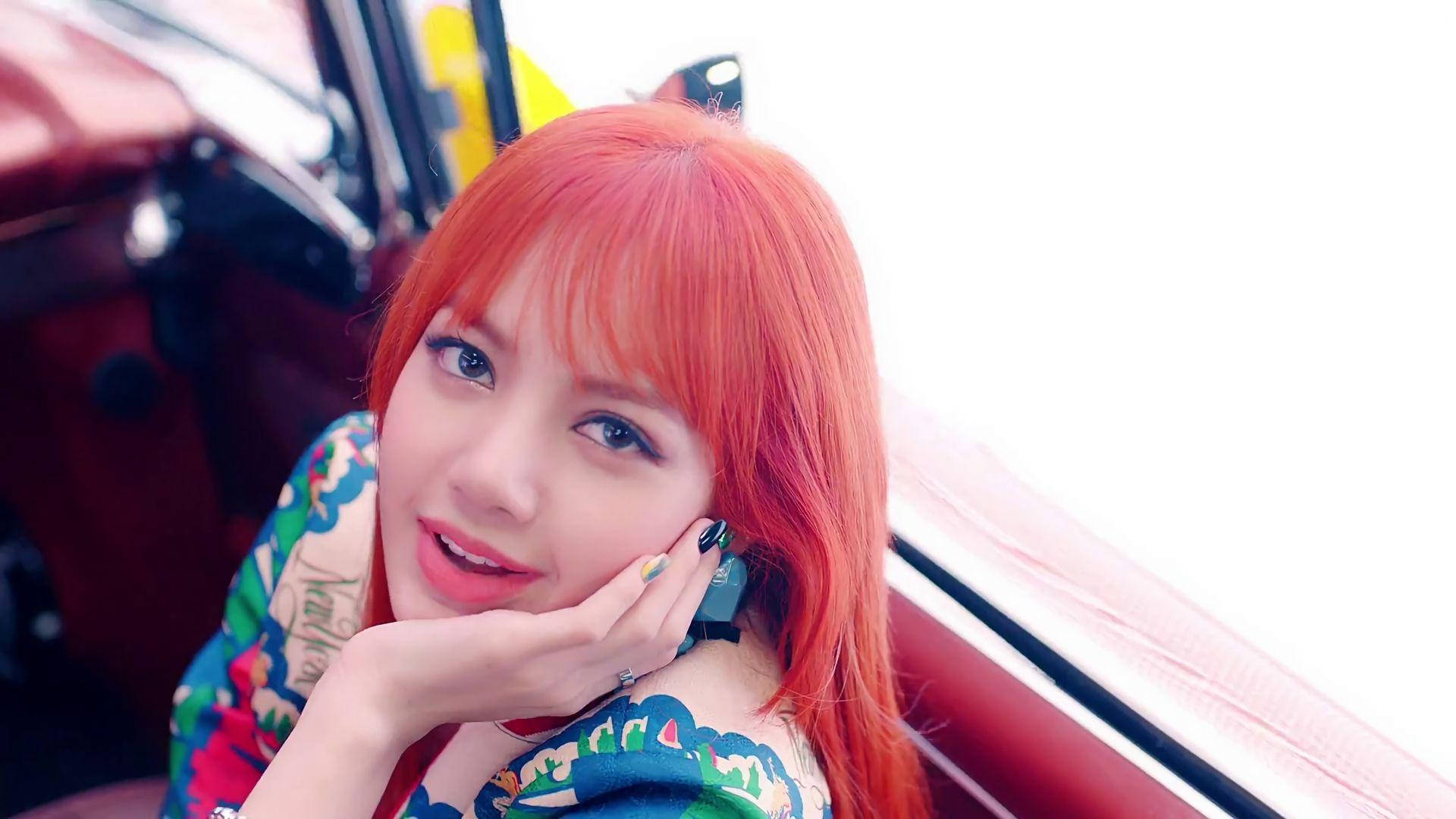 BLACKPINK LISA 音樂錄影帶 壁紙 — 一位擁有鮮豔橙色頭髮的年輕女子，在紅色車內托腮微笑。