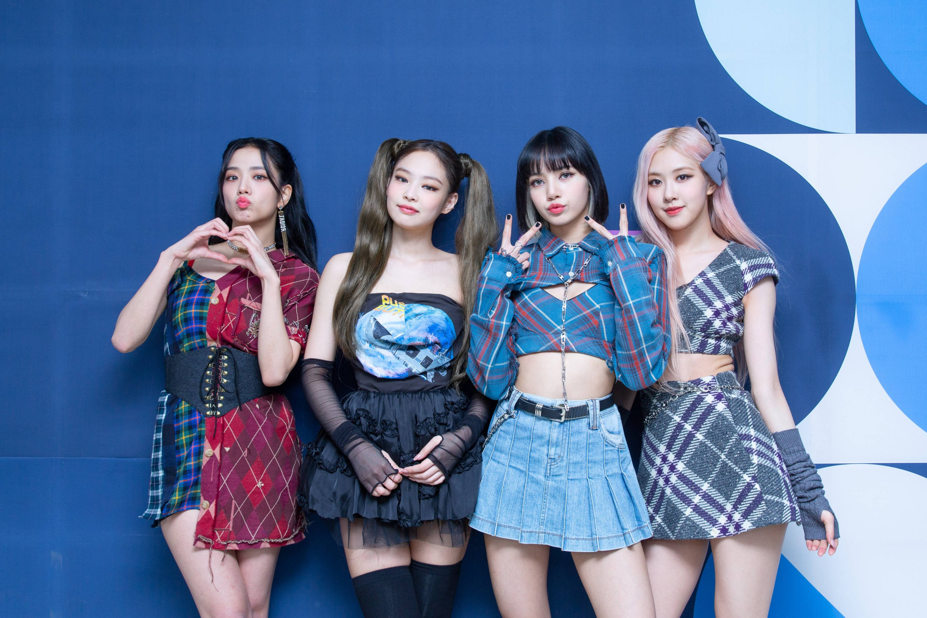 BLACKPINK 成員穿圖案服裝電腦桌面壁紙 壁紙 — 四位時尚的K-pop偶像在搶眼的藍色幾何牆前自信地擺出格仔裝扮的姿勢。