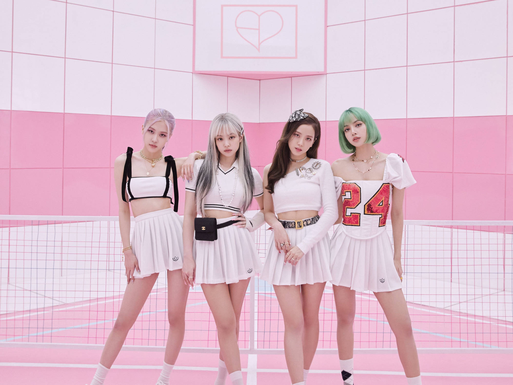 BLACKPINK 成員網球服造型桌面壁紙 壁紙 — 四位時尚女性，頭髮色彩繽紛，穿著相配的白色服裝，在充滿活力的粉紅色網格牆前自信地擺姿勢。