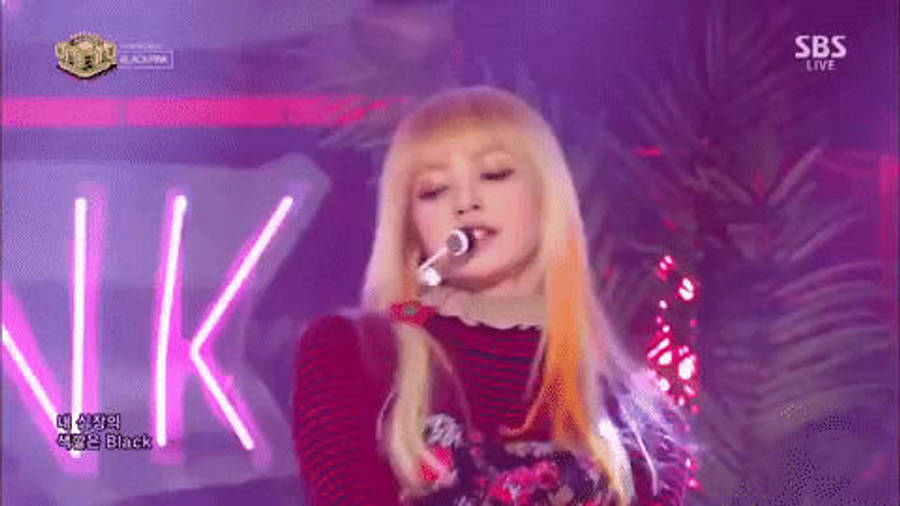 BLACKPINK 梨子展現其震撼風格 壁紙 — 一位金髮女歌手在紫色霓虹燈下表演，背景有棕櫚葉和發光字體。