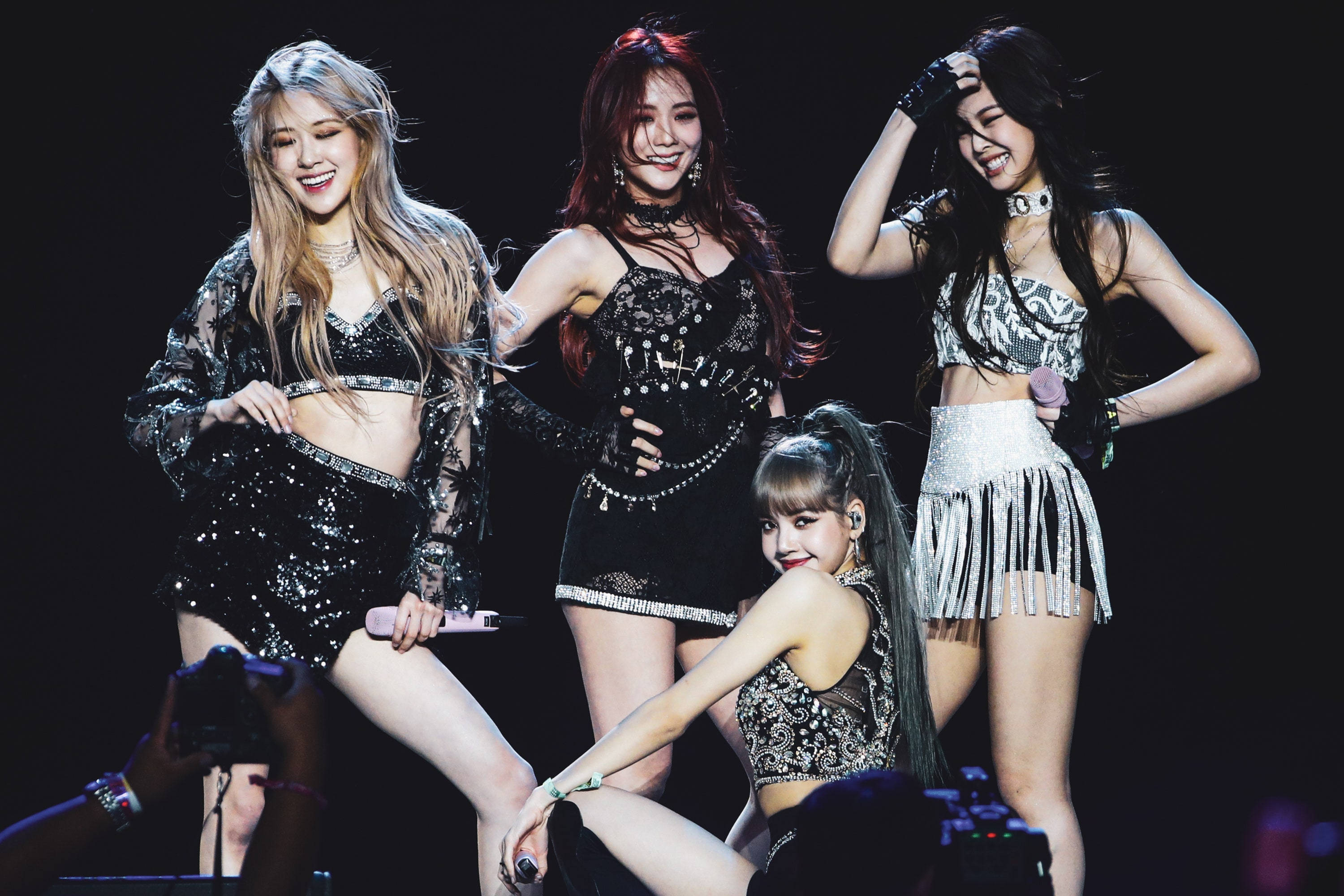 BLACKPINK 舞台後即興照電腦桌面壁紙 壁紙 — 四位身穿閃亮黑色和銀色服裝的K-pop女偶像在明亮的舞台燈光下擺出動態姿勢。