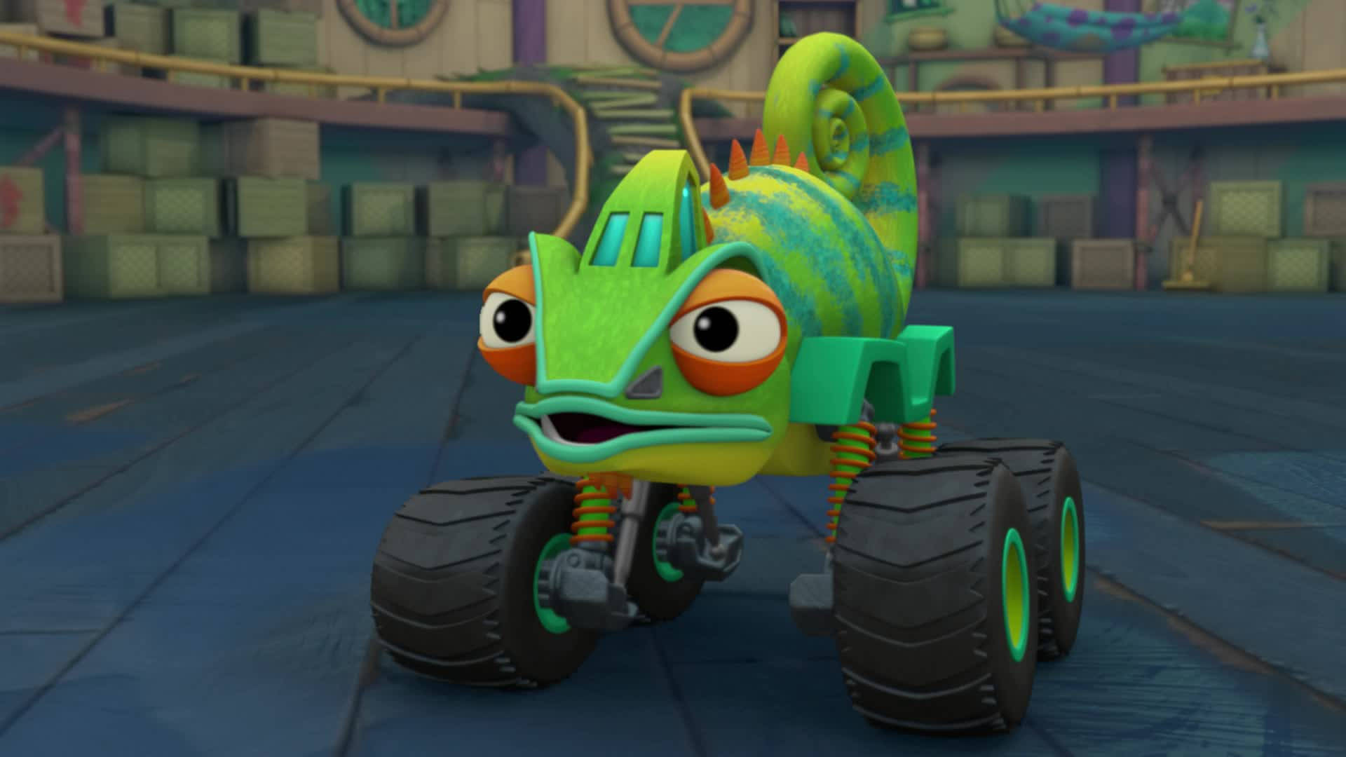 Blaze 與 Monster Machines 賽車冒險 壁紙 — 一輛充滿活力的綠色變色龍怪獸卡車，擁有橙色眼睛和條紋外殼，在色彩繽紛的倉庫環境中準備就緒。