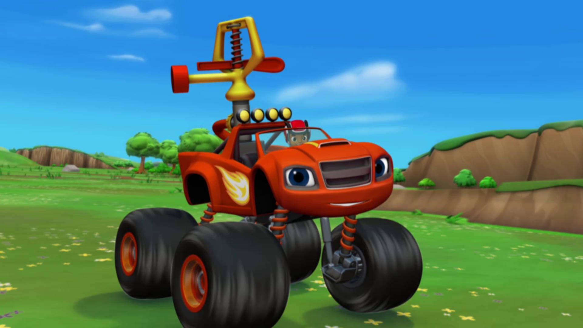 Blaze 與 Monster Machines 洒水器造型 壁紙 — 一輛有大眼睛和火焰貼紙的橙色開心怪獸卡車，在晴朗的藍天下駛過陽光明媚的草地。
