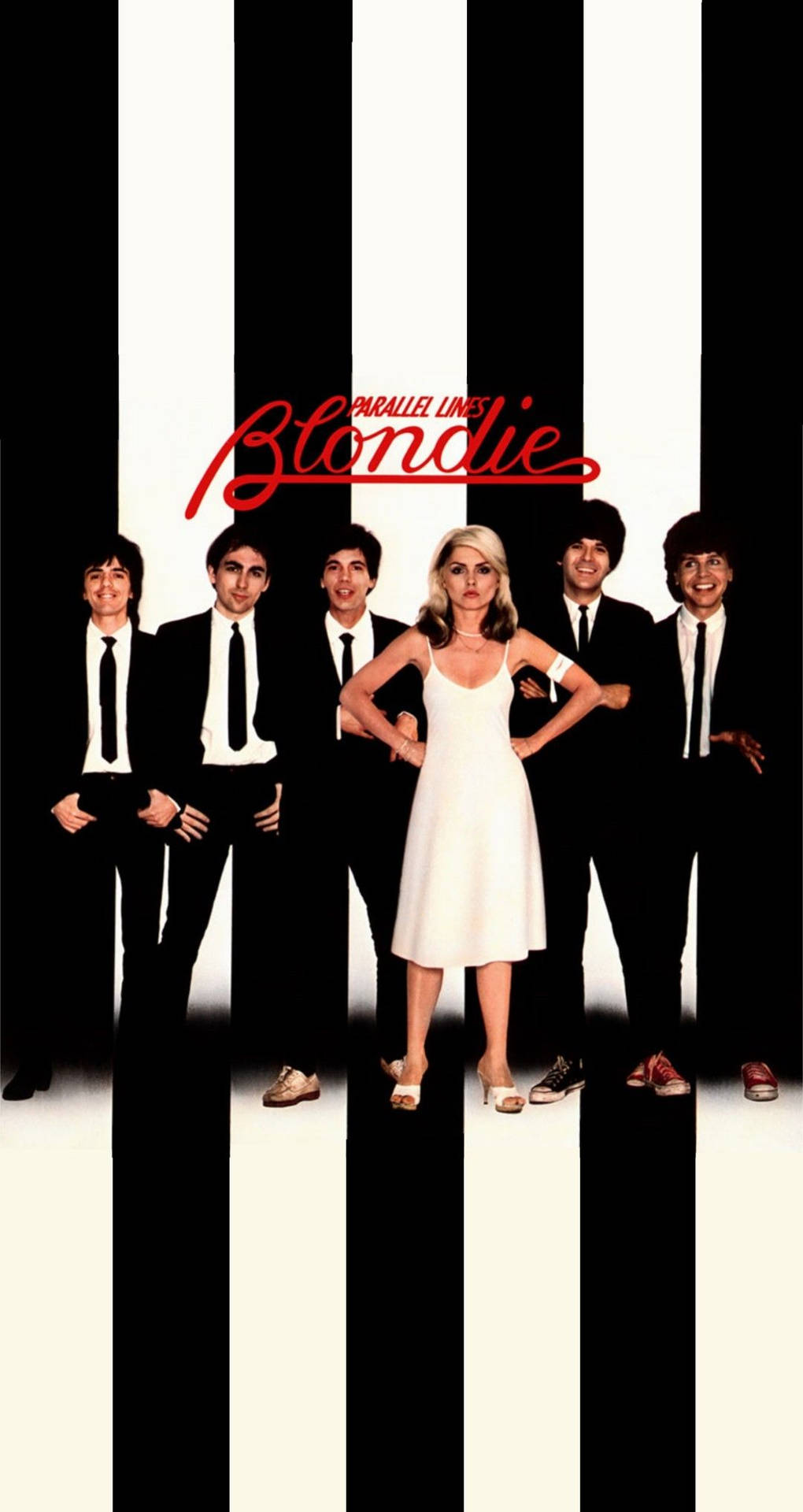 Blondie 樂隊成員身穿黑色西裝，與身穿白色連衣裙的金髮女子在黑白條紋前擺姿勢。