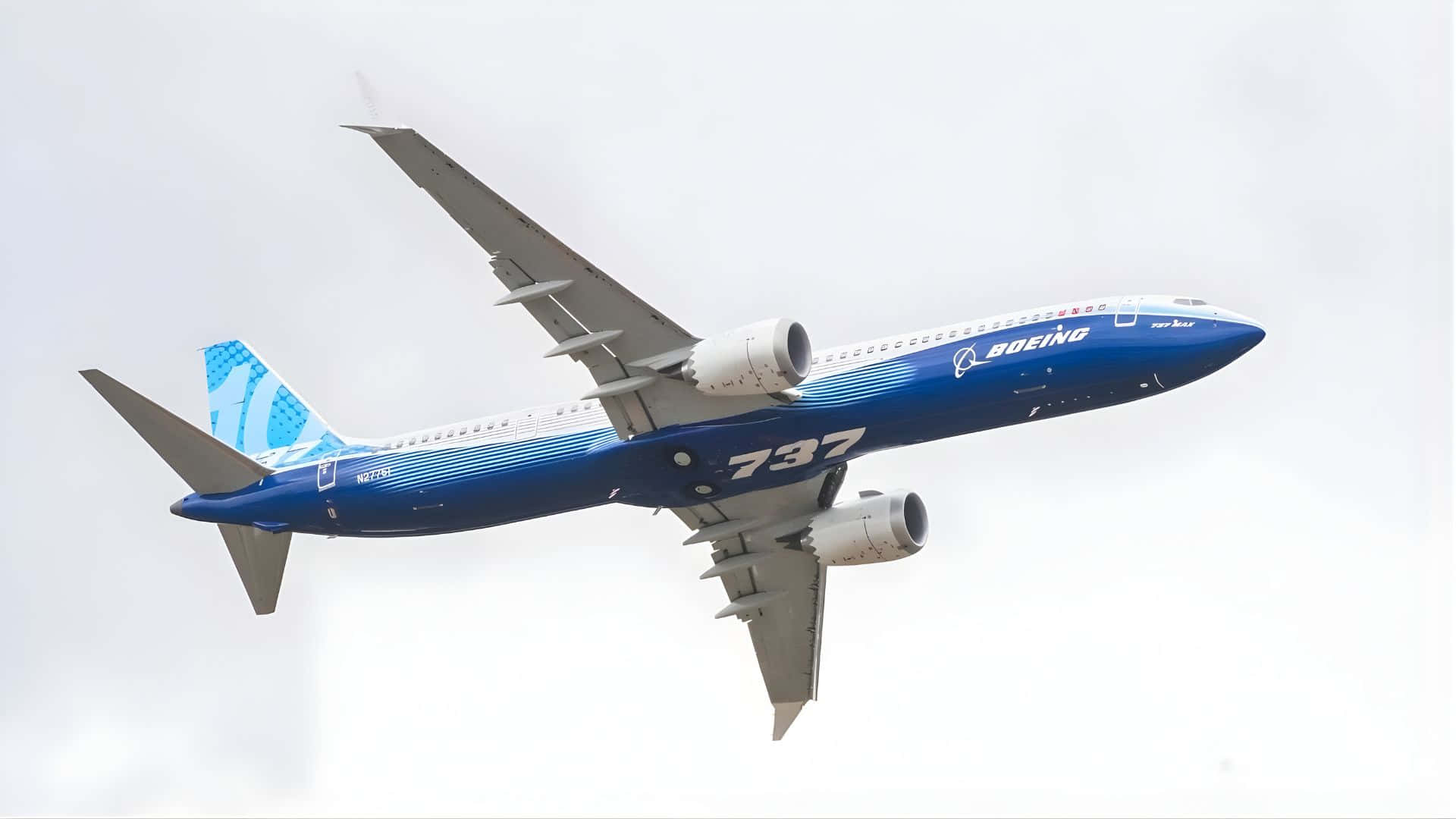  壁紙 — 一架藍白相間的波音737飛機在陰天中翱翔，起落架已收起。