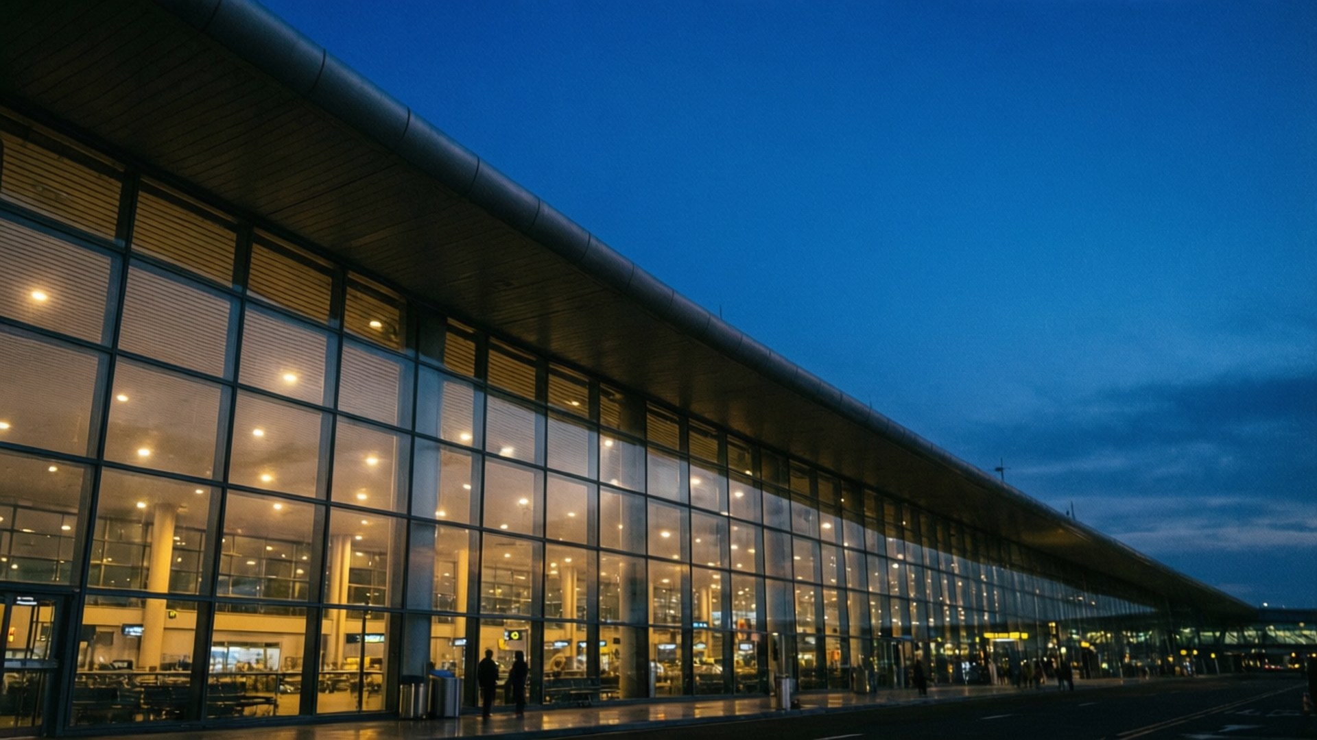 黃昏時分的現代機場客運大樓，內部燈光閃爍，外面有人