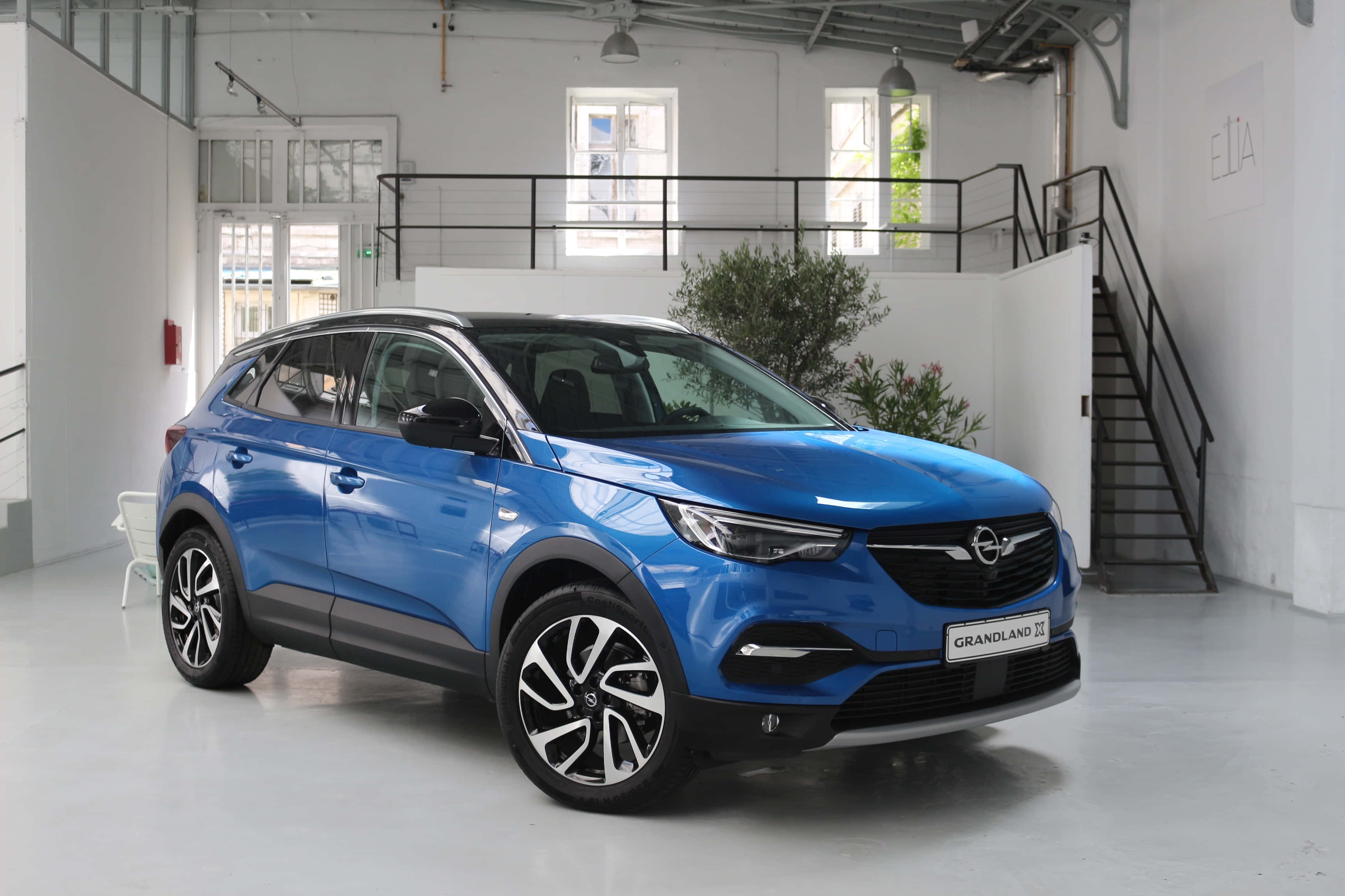 Opel Grandland X 桌布 壁紙 — 一輛充滿活力的藍色Opel Grandland X SUV在一個簡約的白色工業工作室中展示，配有自然光。