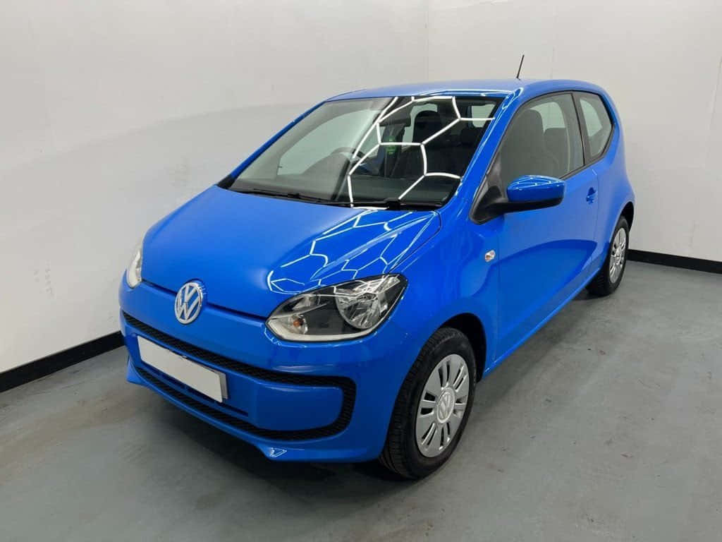  壁紙 — 一輛鮮藍色Volkswagen up!小型車，引擎蓋和擋風玻璃上有幾何白色貼紙，停放在室內灰色地板上，背景為白色牆壁。