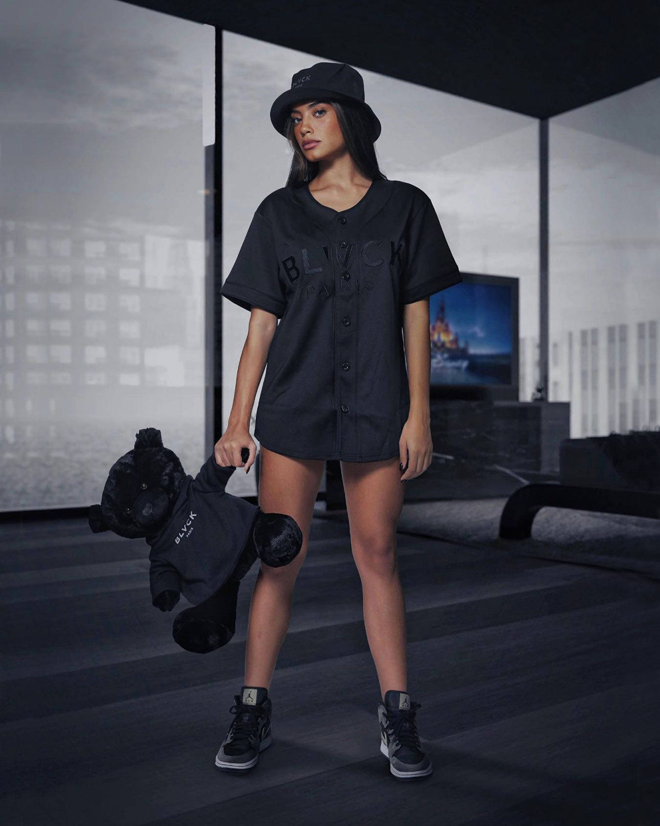 穿黑色衣服的女性在現代房間裡抱著黑色泰迪熊。