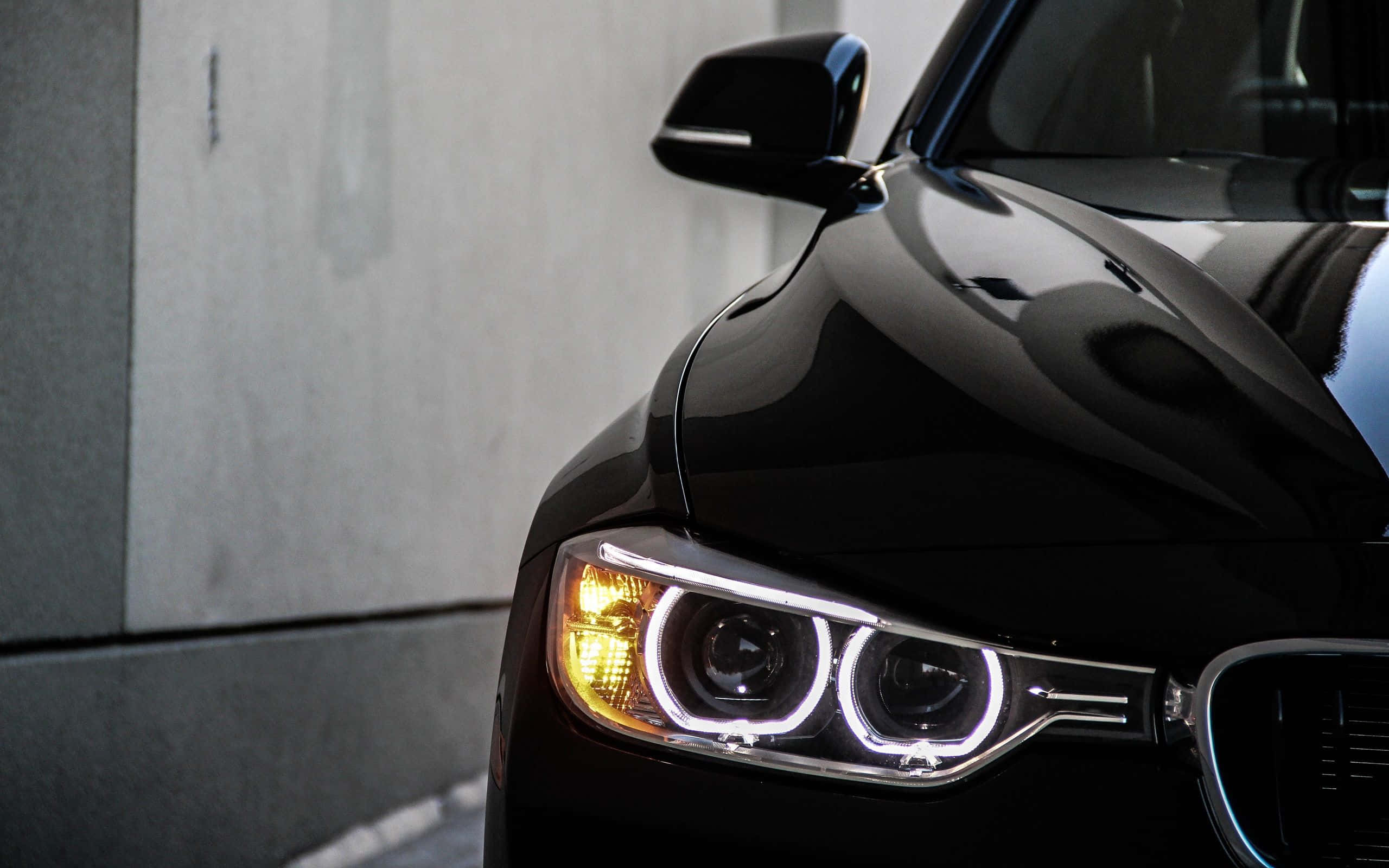 BMW 328——德國經典標誌 壁紙 — 黑色流線型汽車發光車頭燈的特寫，背景為混凝土牆。