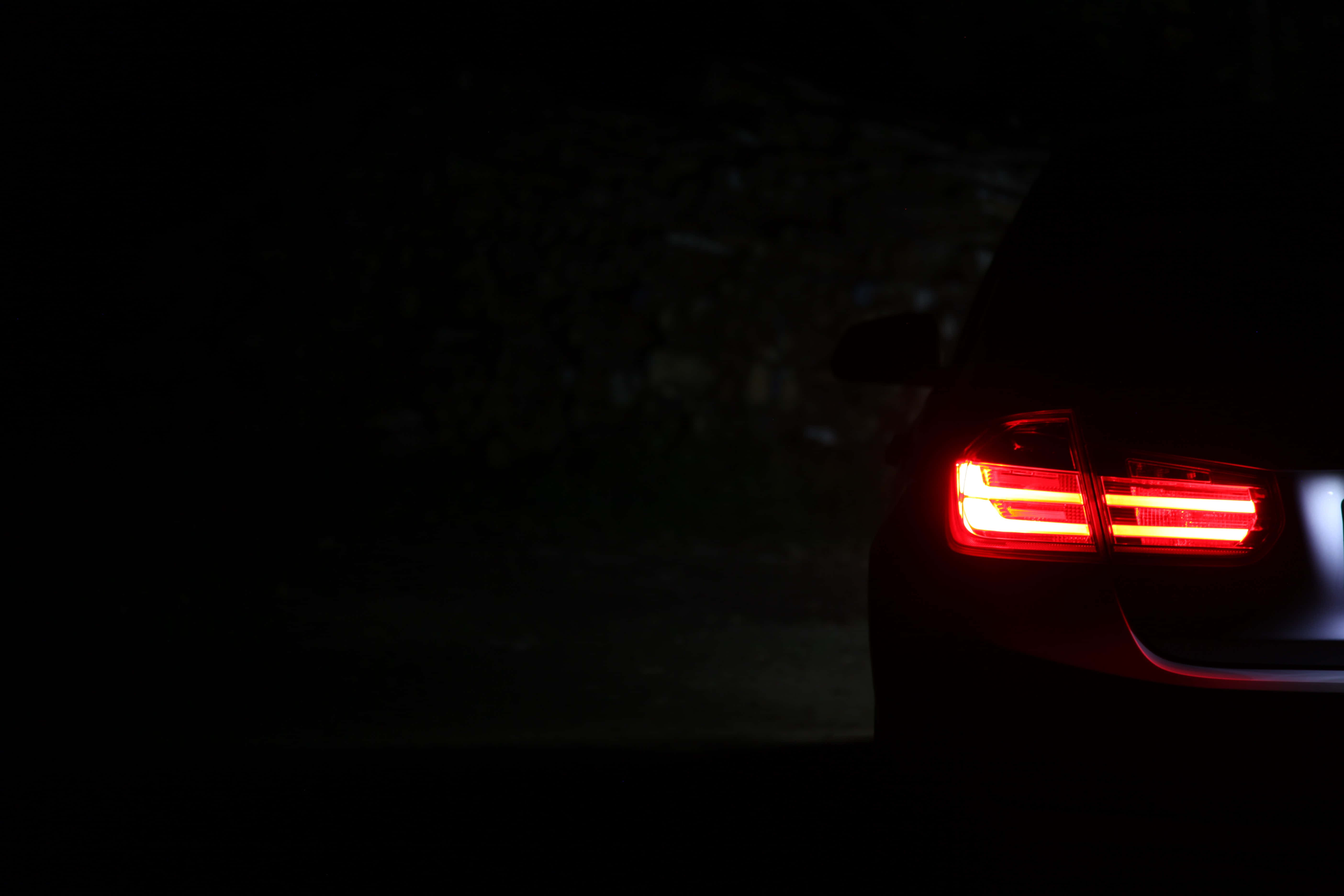 從前格柵到尾部，經典BMW 328全貌 壁紙 — 一輛汽車發光的紅色尾燈刺穿了夜間路邊場景的黑暗。
