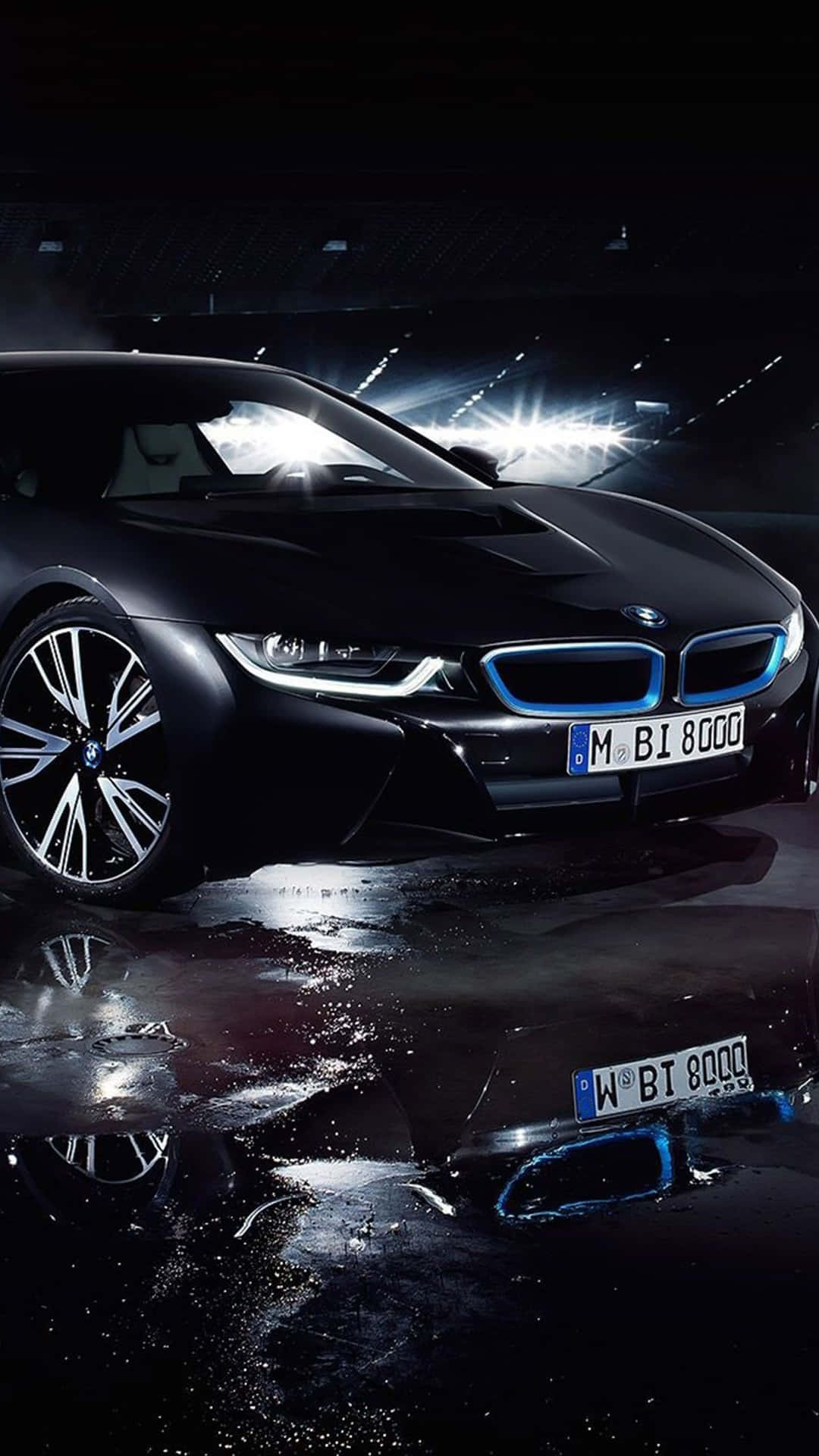 黑色BMW i8跑車，藍色燈光在體育館燈光下反射在潮濕的瀝青路面上。