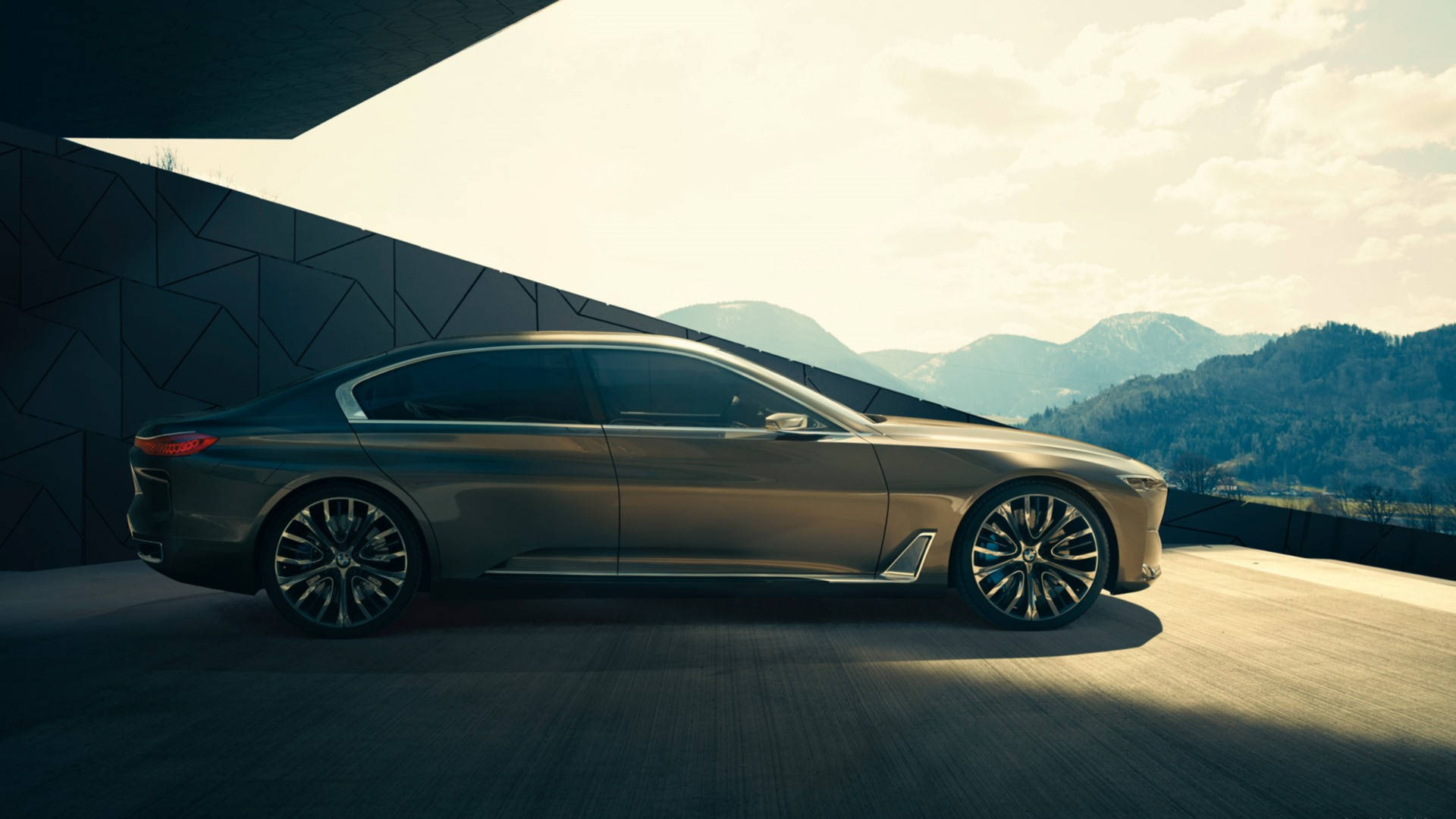 BMW 豪華汽車駛出 壁紙 — 一輛時尚的金屬色轎車停放在現代幾何平台上，背景是山脈，天空柔和金黃。
