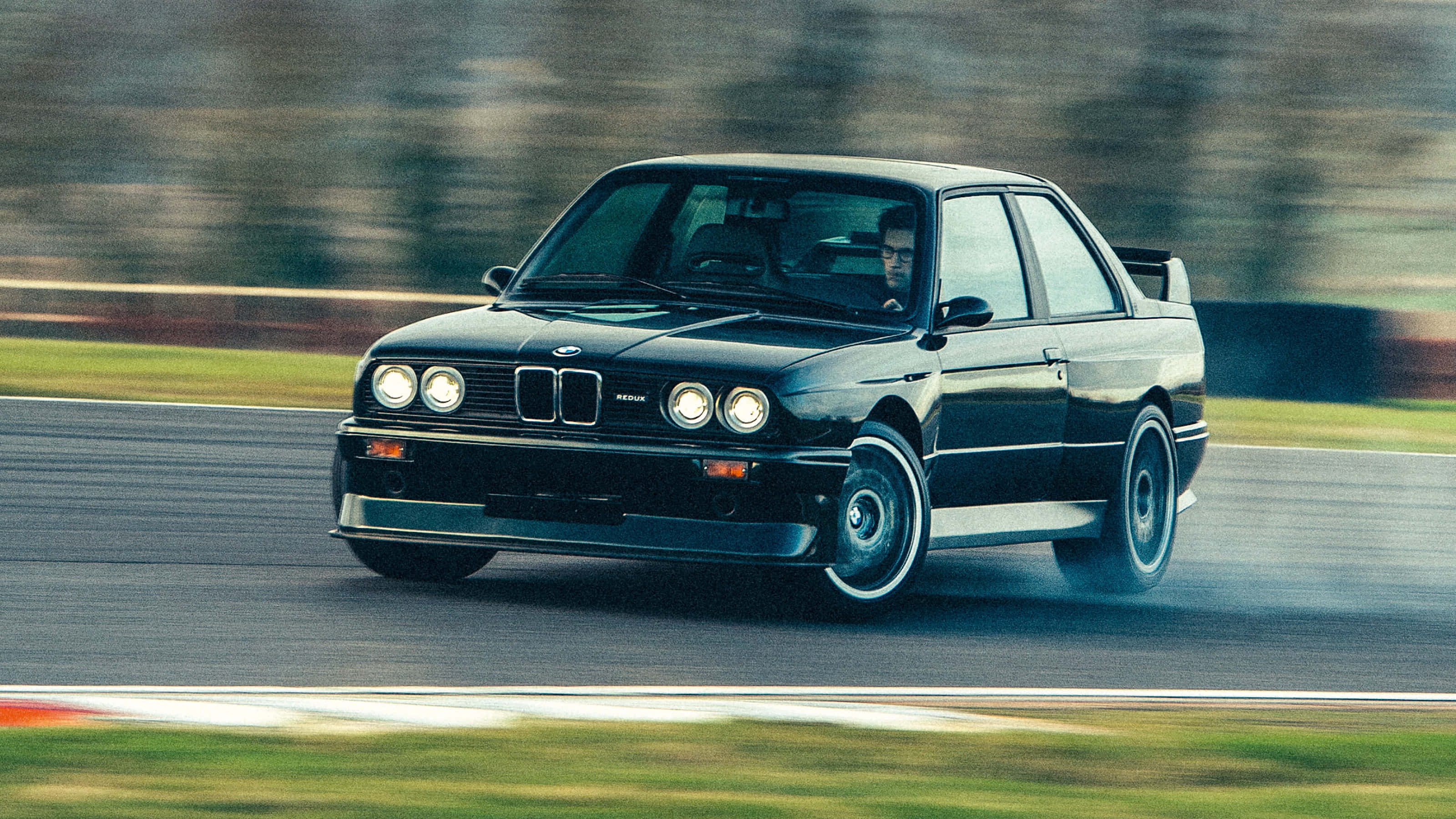 在陽光下閃耀的BMW 6系列轎跑 壁紙 — 一架時尚的黑色BMW M3在賽道上奔馳，動態模糊效果傳達高速與精準。