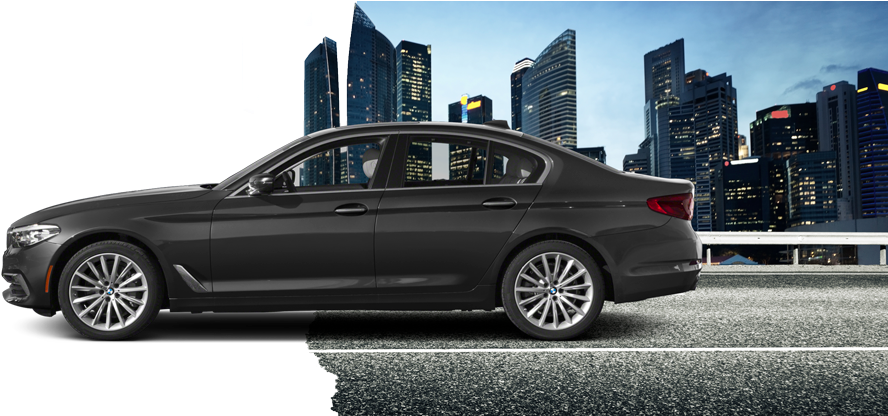 BMW 車型都市背景 壁紙 — 一輛時尚的黑色轎車在黃昏時分行駛在城市高速公路上，背景是燈火通明的摩天大樓。