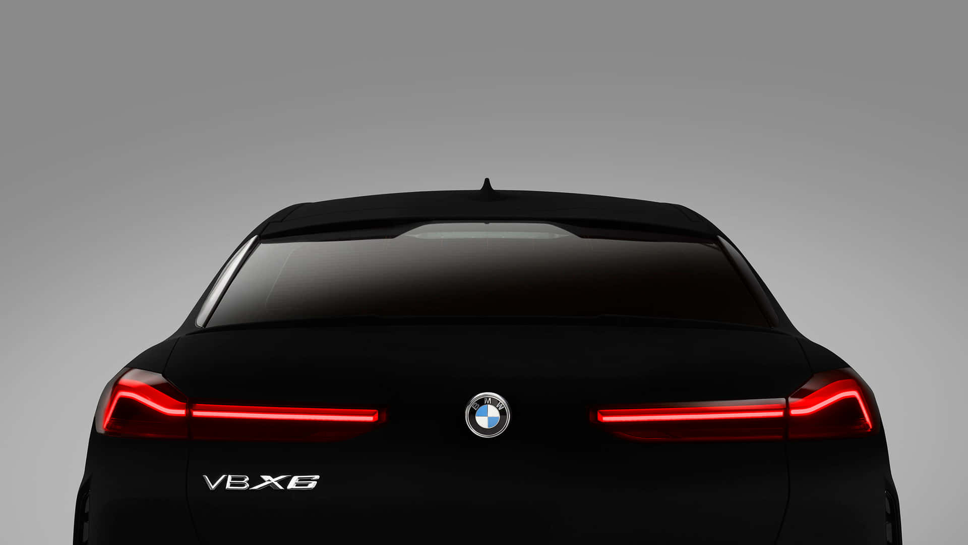 灰色背景上，黑色BMW V8X6後視圖，紅色尾燈亮起。