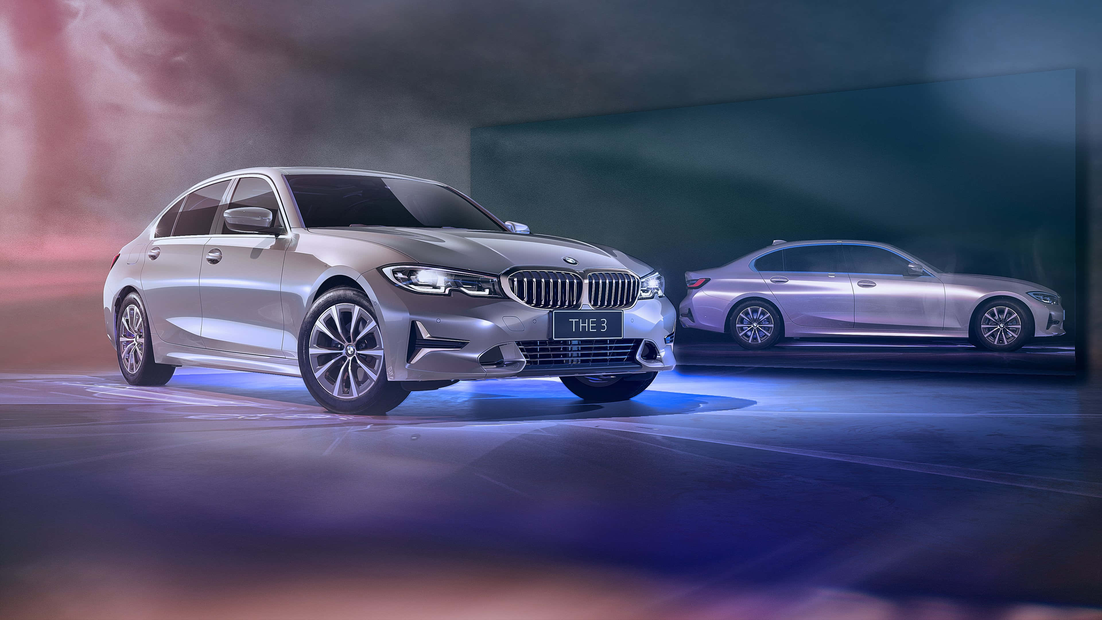奢華銀色 BMW 壁紙 — 一輛時尚的銀色BMW 3系轎車在戲劇性的藍色和粉紅色工作室燈光下閃耀，背後有半透明的倒影。
