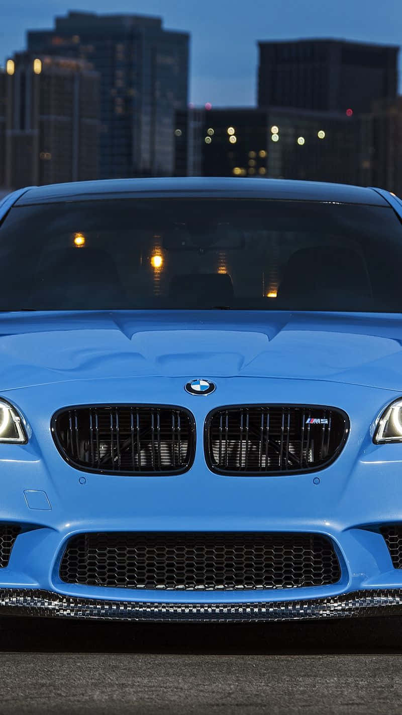 藍色BMW M5跑車停放在黃昏的城市天際線前。
