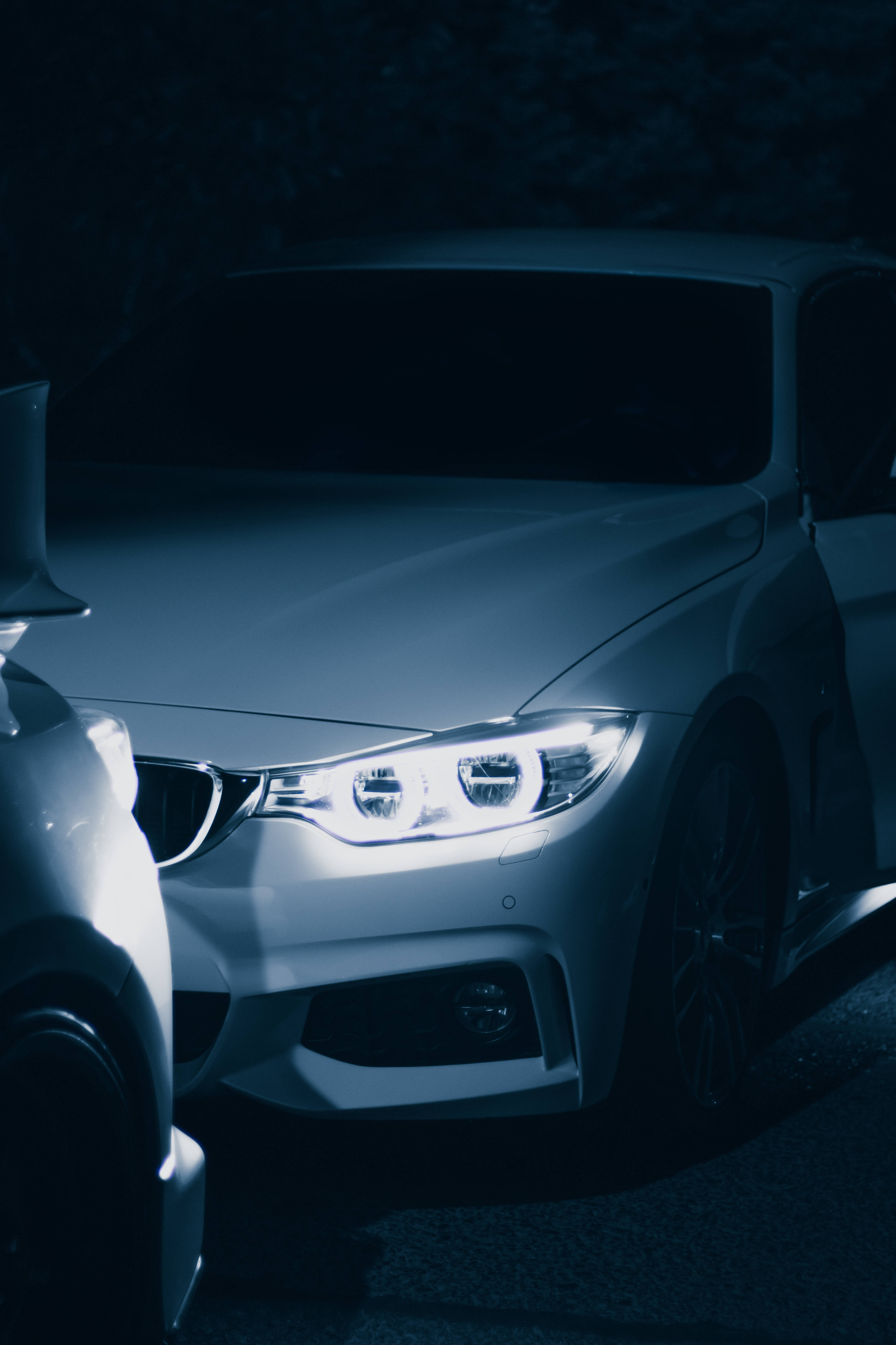卓越優雅 - BMW M系列頭燈 壁紙 — 一輛時尚的白色跑車在黑暗的夜間環境中，在自己的車頭燈下發光。