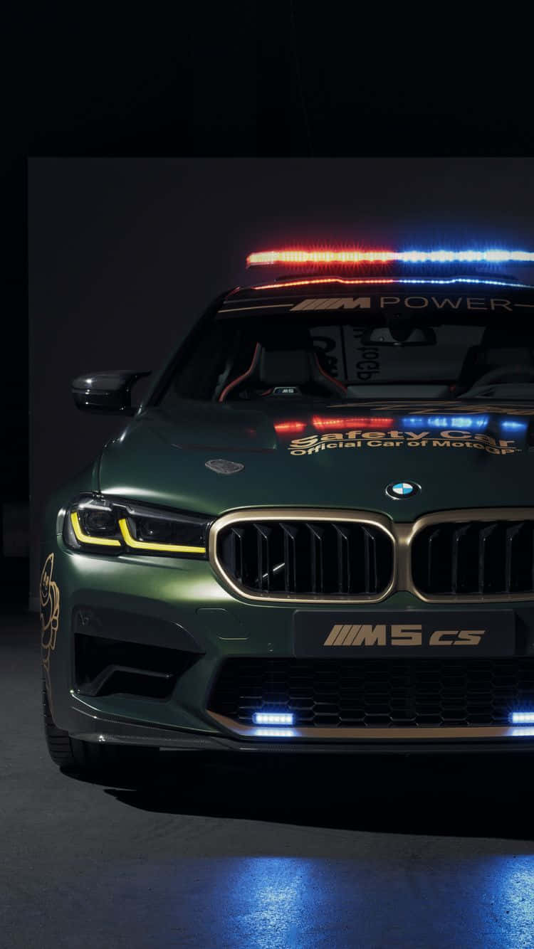 深綠色BMW M5 CS安全車在黑暗的攝影棚中閃爍著燈光。