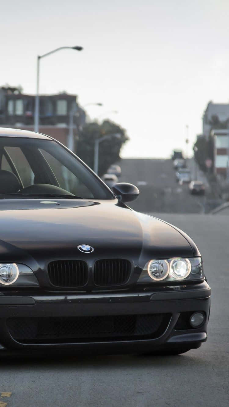 黑色BMW汽車停放在城市街道上，背景有建築物和街燈。