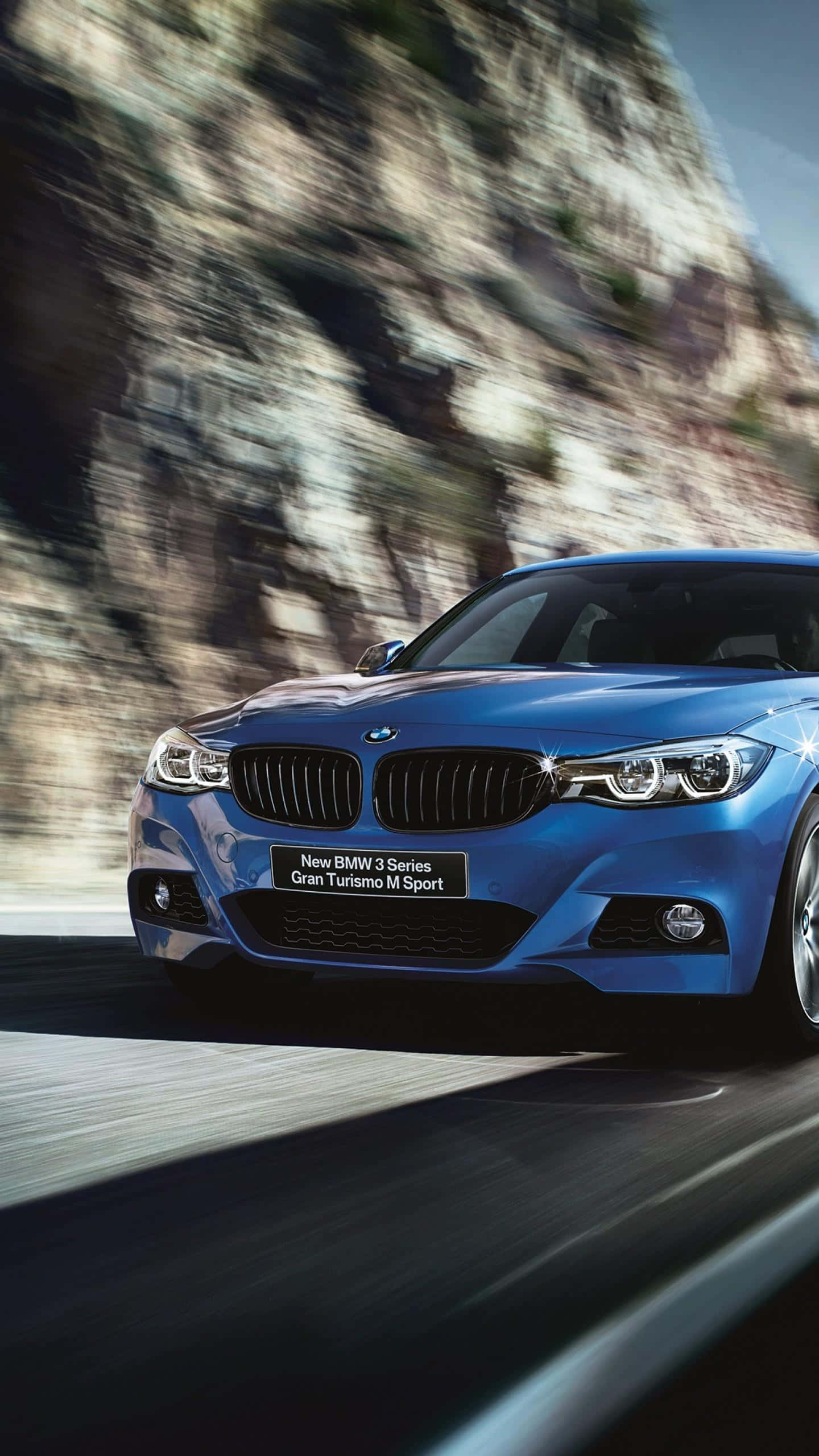 優雅的BMW M系列車款 壁紙 — 一輛充滿活力的藍色BMW M Sport汽車沿著蜿蜒的山路疾馳，模糊的岩石懸崖飛掠而過。