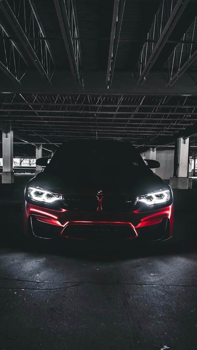 一輛黑色跑車，帶有紅色飾邊和明亮的車頭燈，在黑暗的停車場中。