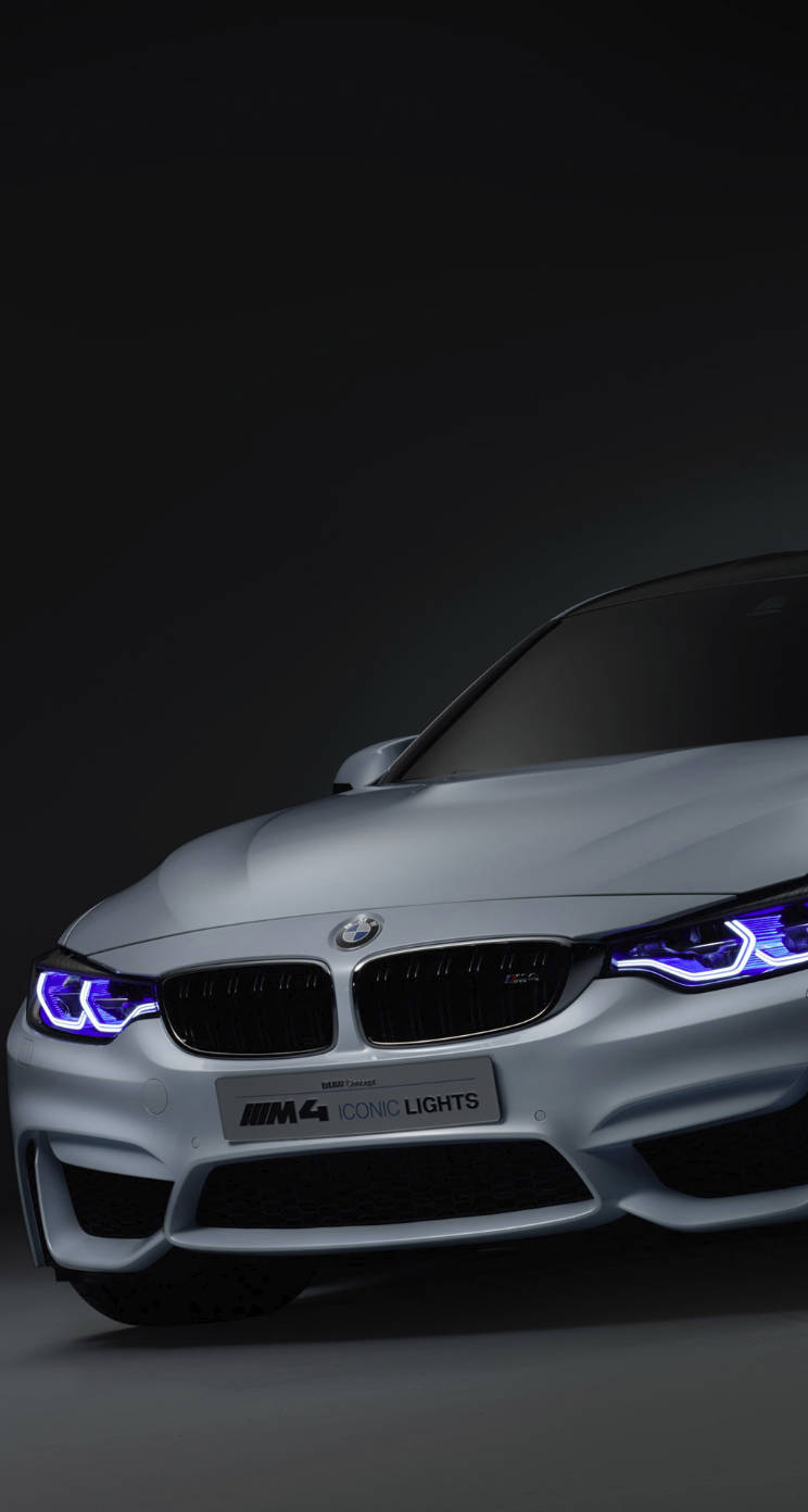 在黑暗的攝影棚環境中，銀色BMW M4配備藍色頭燈。