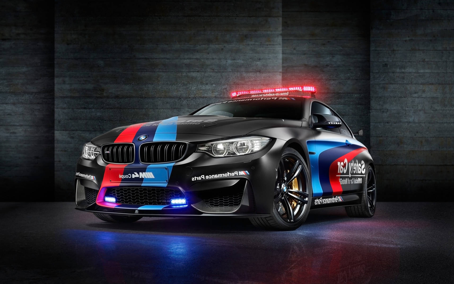 黑色BMW M4 Coupe安全車，帶有藍紅白塗裝，在攝影棚燈光下閃耀。