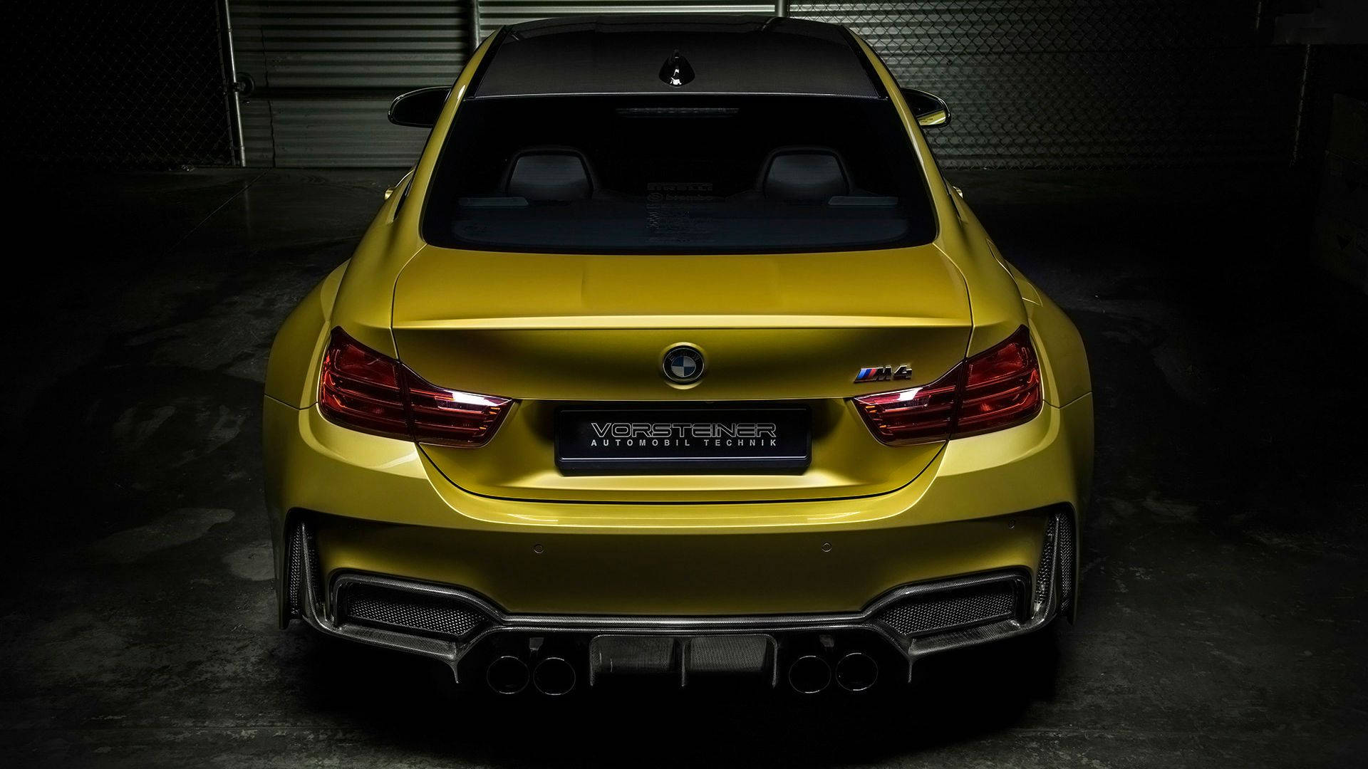 BMW M4 系列黃色款 壁紙 — 一輛亮黃色BMW M4在昏暗車庫中的後視圖，戲劇性的燈光突出了其運動型排氣管和尾燈。