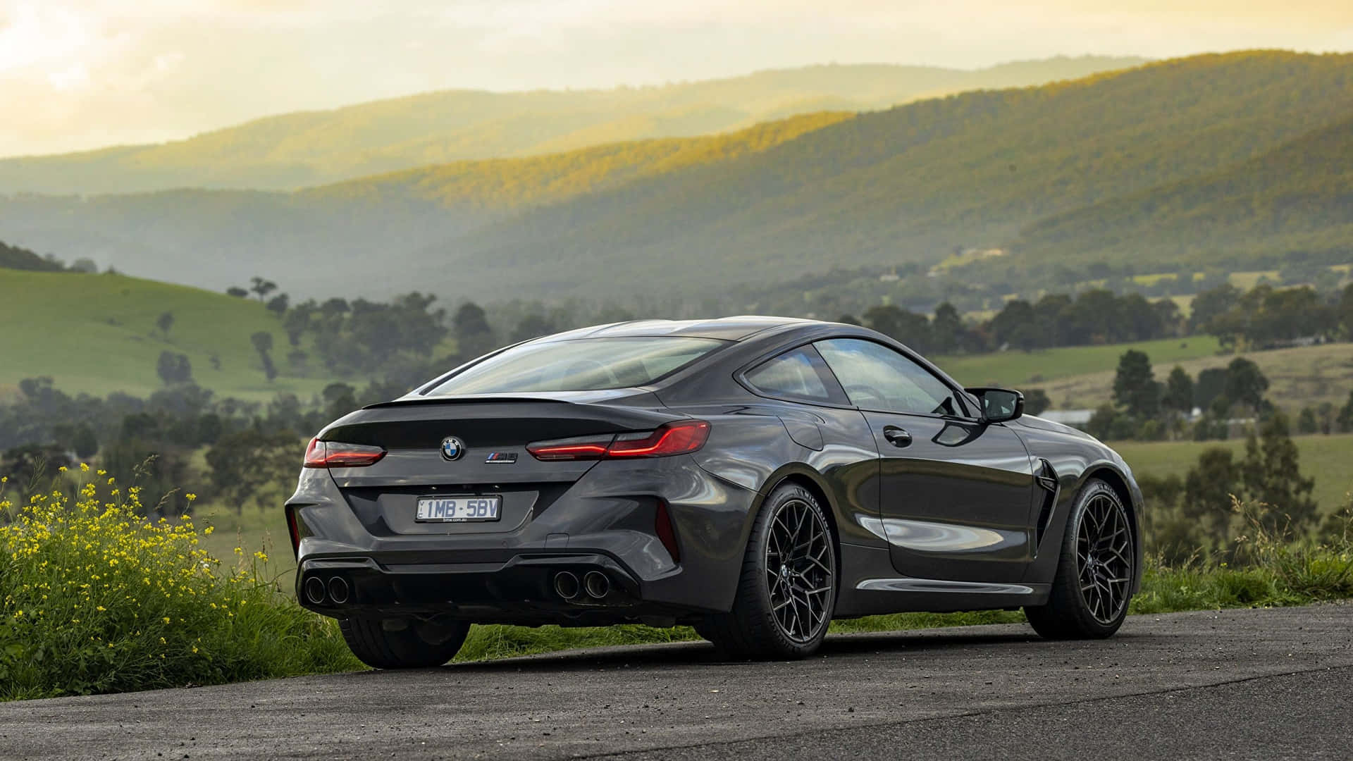 日落時分，深灰色BMW M8 Coupe停泊在風景如畫的鄉村道路上。