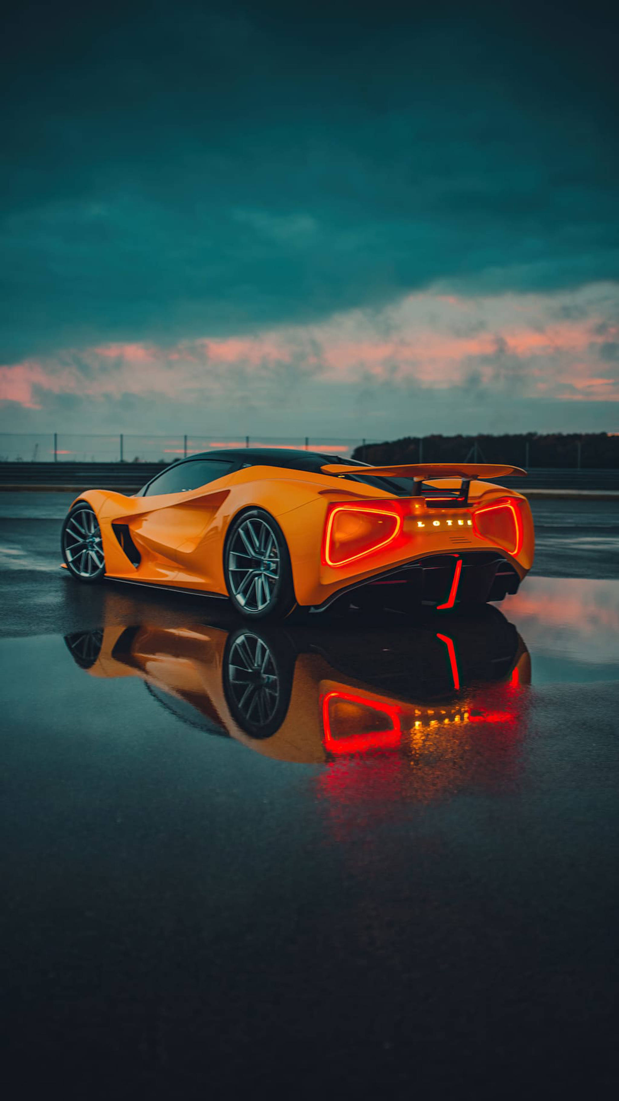 酷炫BMW跑車 壁紙 — 一輛充滿活力的橙色跑車，帶有發光的紅色尾燈，在暮色天空下的濕瀝青上反射。