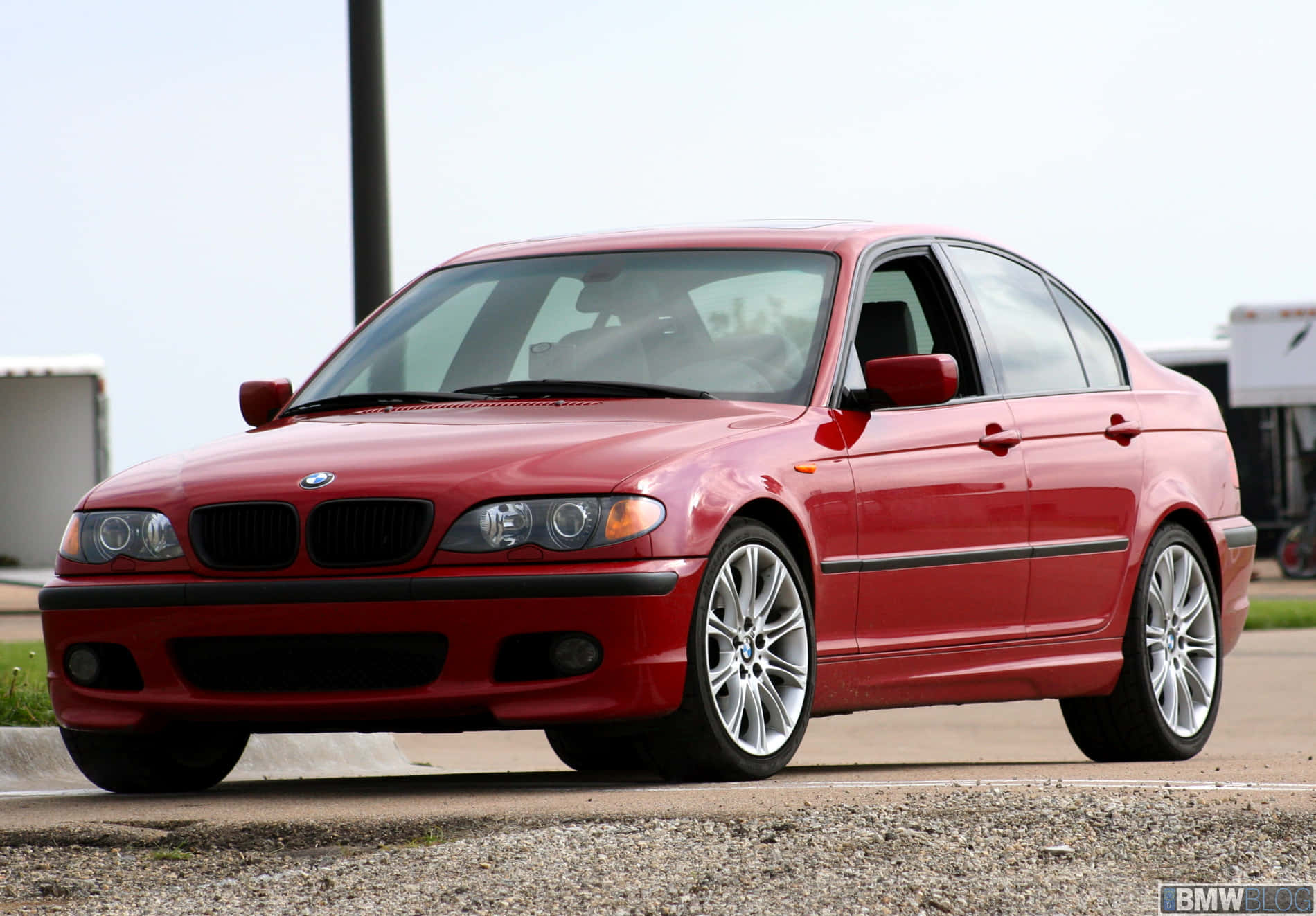 彰顯品味：BMW的豪華視野 壁紙 — 一輛亮麗的紅色BMW 3系房車停在碎石上，配備銀色合金輪圈，在明亮的日光下。