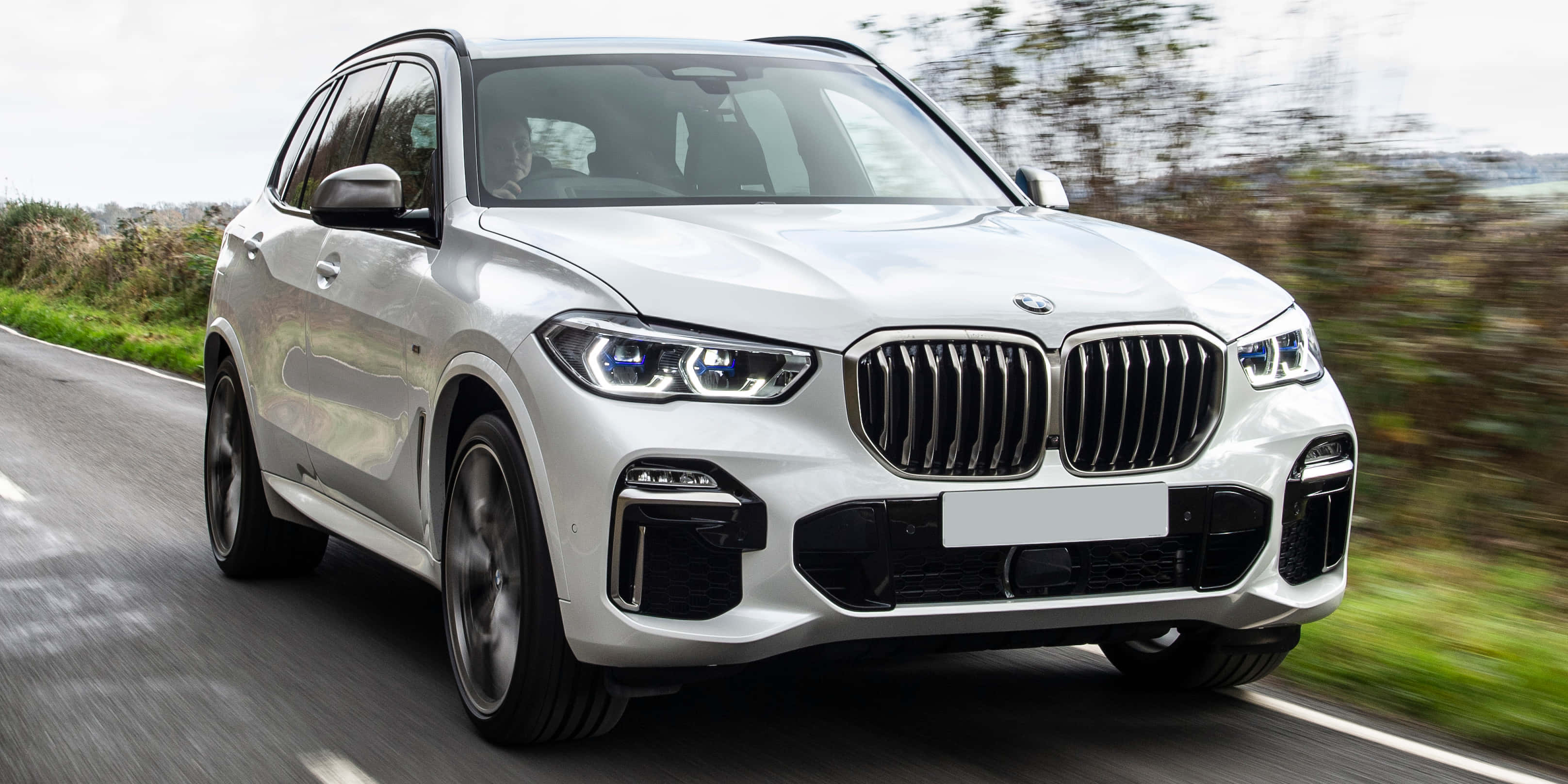炫酷BMW X5在路上 壁紙 — 一輛時尚的白色BMW X5 SUV在蜿蜒的道路上疾馳，模糊的綠色植物呼嘯而過。