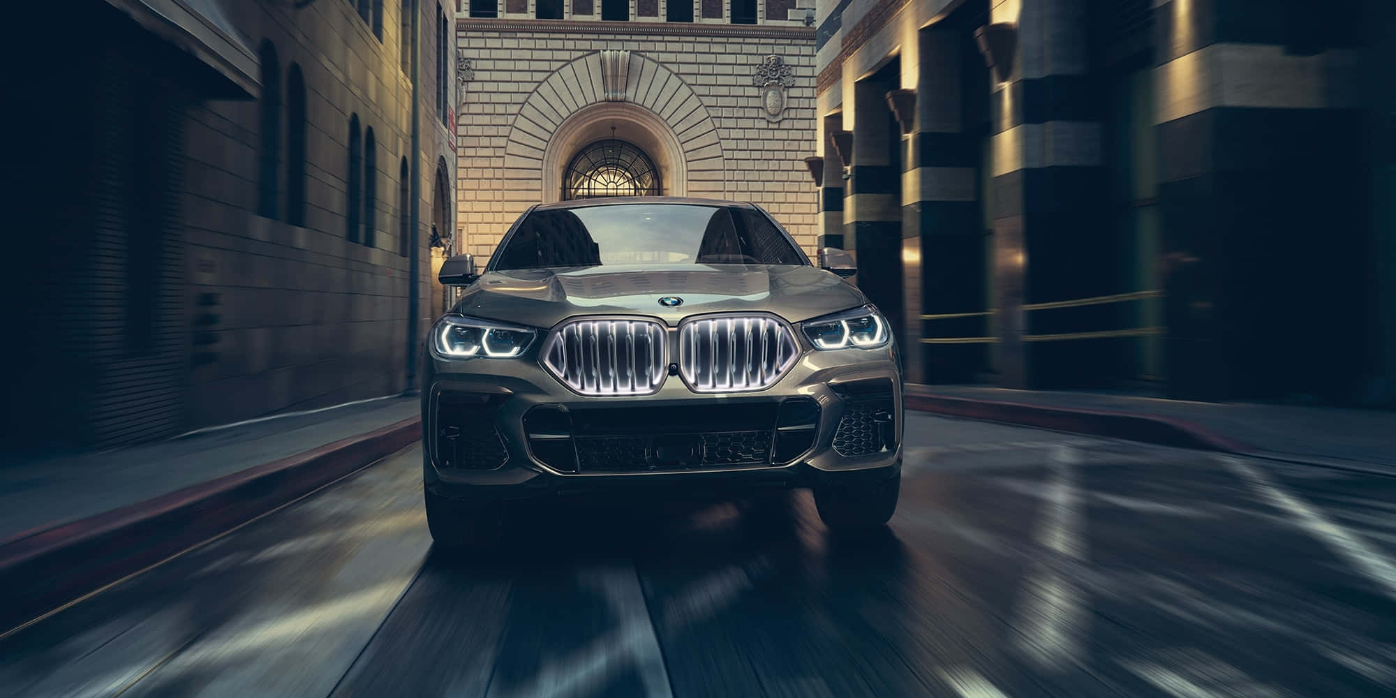 BMW X6 M 停泊在綠意盎然的景觀中 壁紙 — 一輛時尚的黃金寶馬SUV在狹窄的城市小巷中飛馳，帶有動態模糊和溫暖的建築照明。