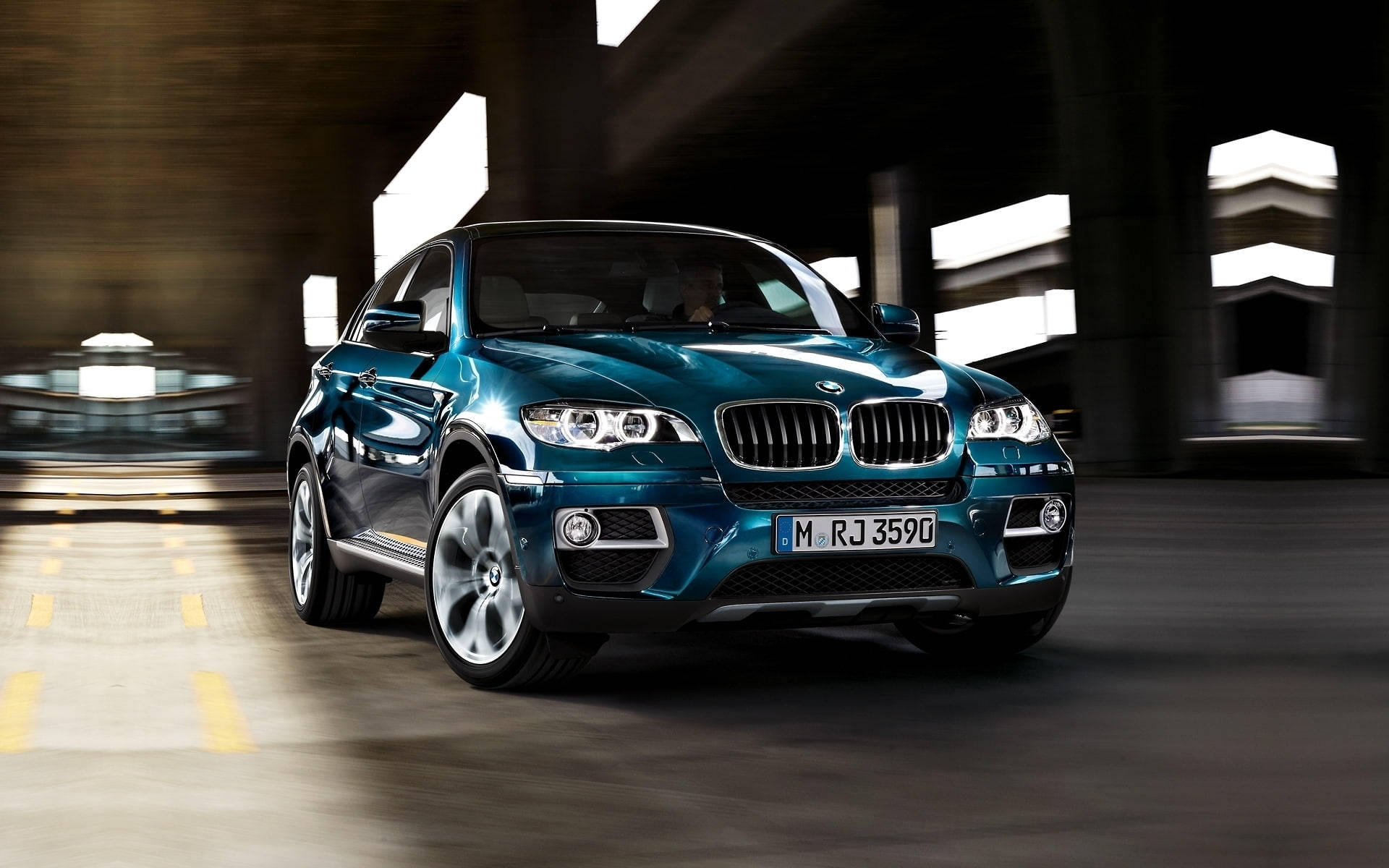 BMW X6 M 汽車 壁紙 — 一台時尚的藍綠色BMW X6在現代隧道中疾馳，動態模糊效果凸顯其動感設計。