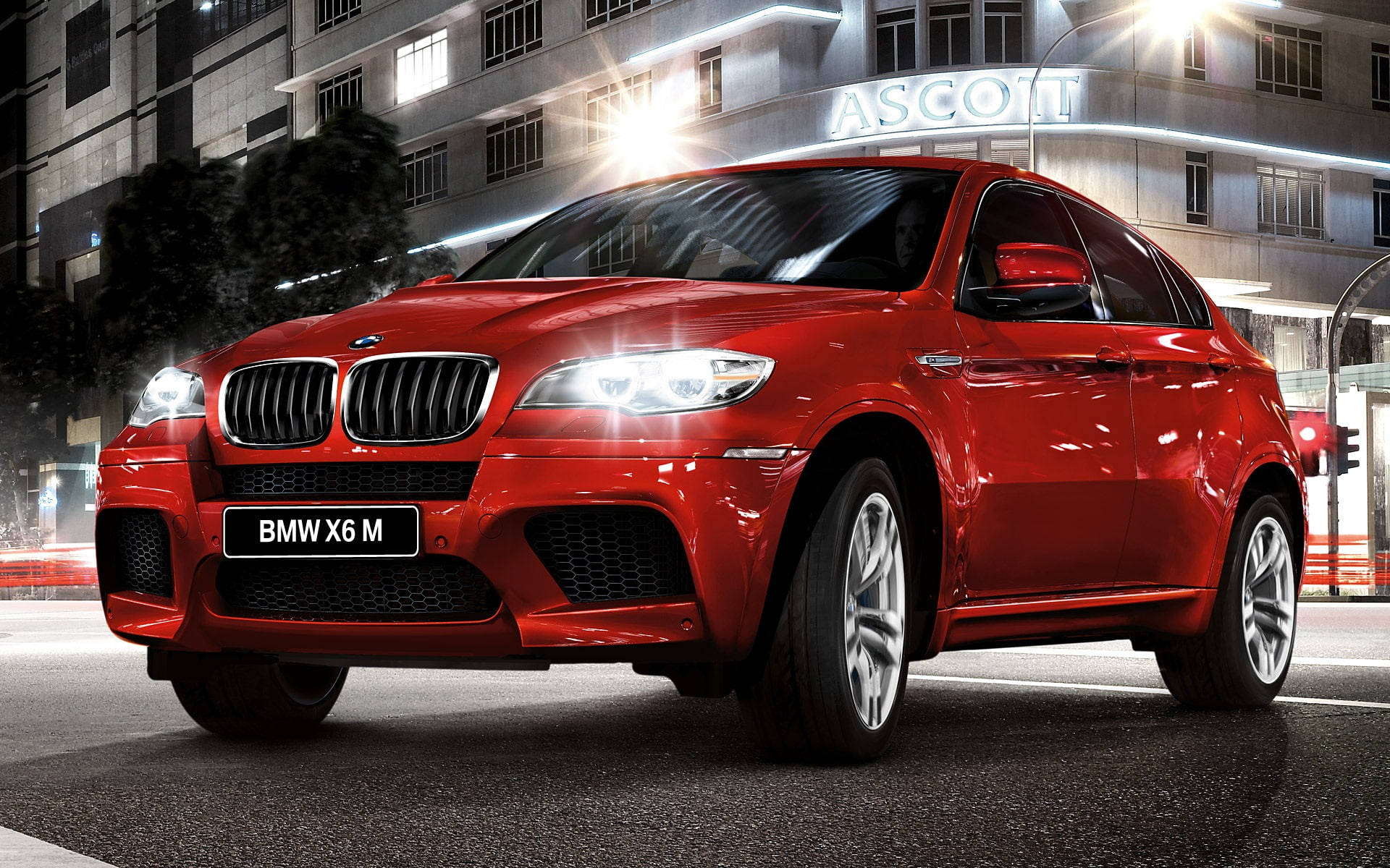 BMW X6 M近距離特寫 壁紙 — 一輛亮紅色BMW X6 M SUV在夜間濕滑的街道上閃耀著城市燈光，背景是一座燈火通明的建築物。