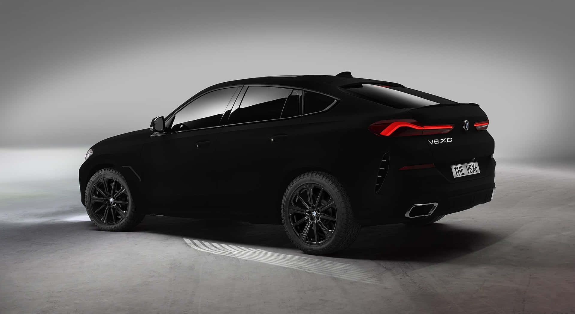 黑色BMW X6 V8X6 SUV，在工作室環境中帶有發光的紅色尾燈。