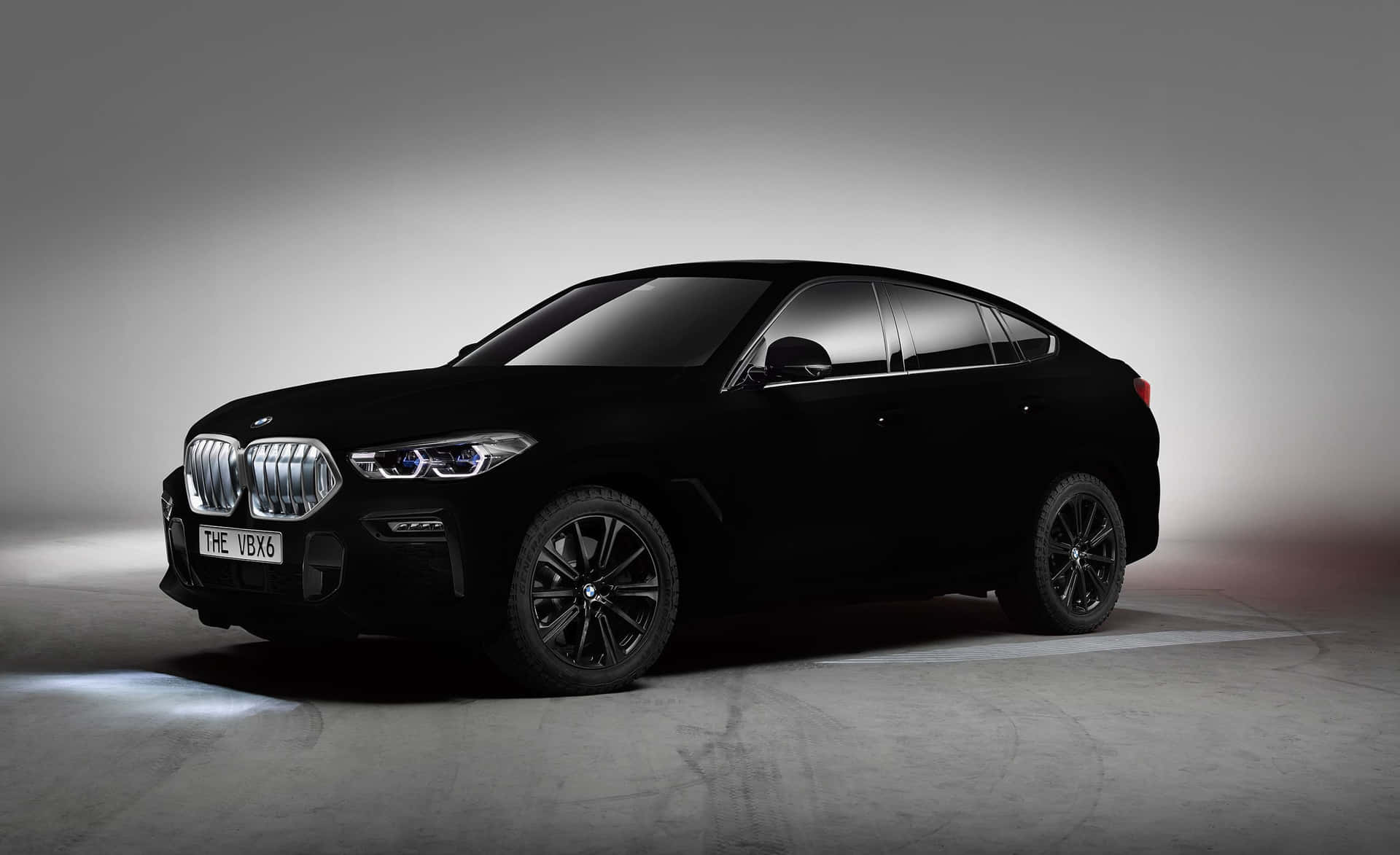 黑色BMW X6 SUV在工作室中，配有聚光燈和灰色背景