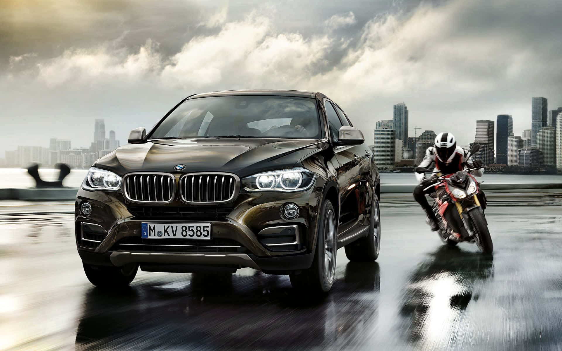 酷炫BMW X6 壁紙 — 一架時尚黑色BMW X6 SUV與一架紅色電單車在暴風雨天空下，於濕滑的城市橋上並肩飛馳。