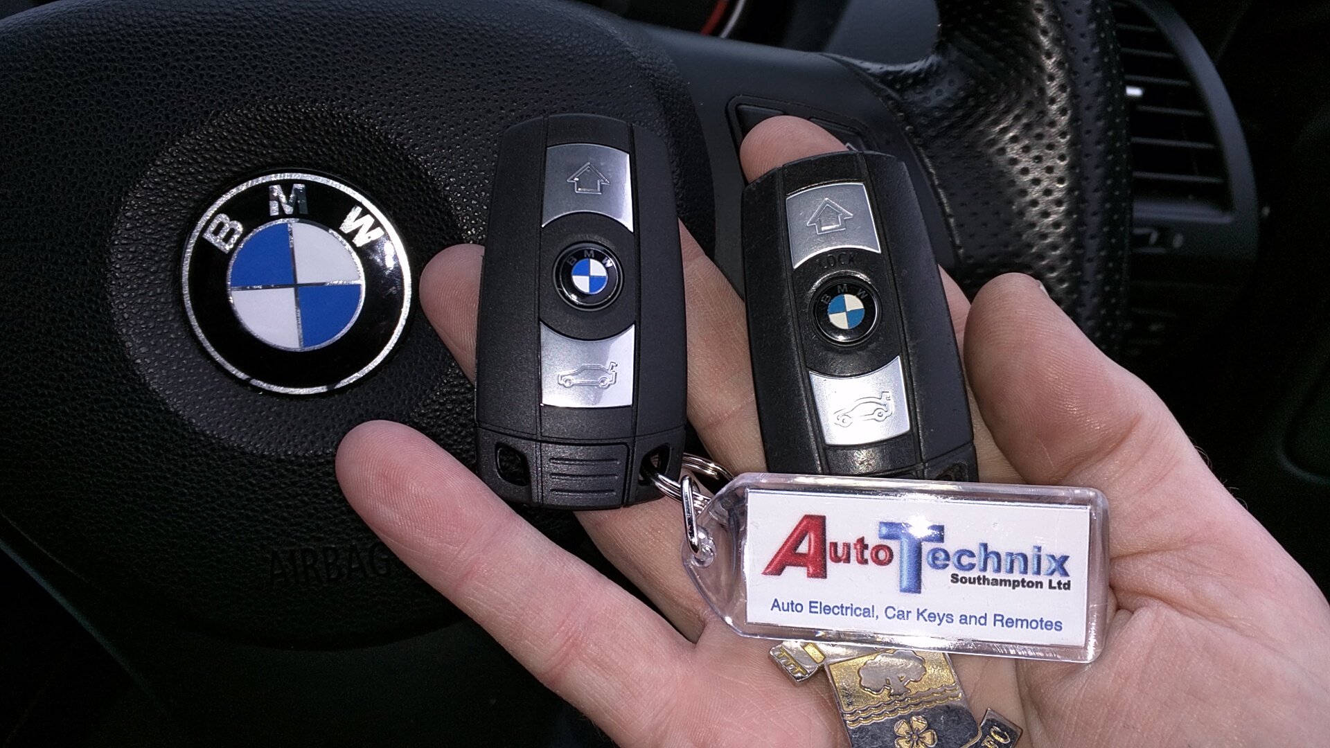 手在方向盤附近拿著帶有Auto Technix鎖匙扣的BMW車匙。