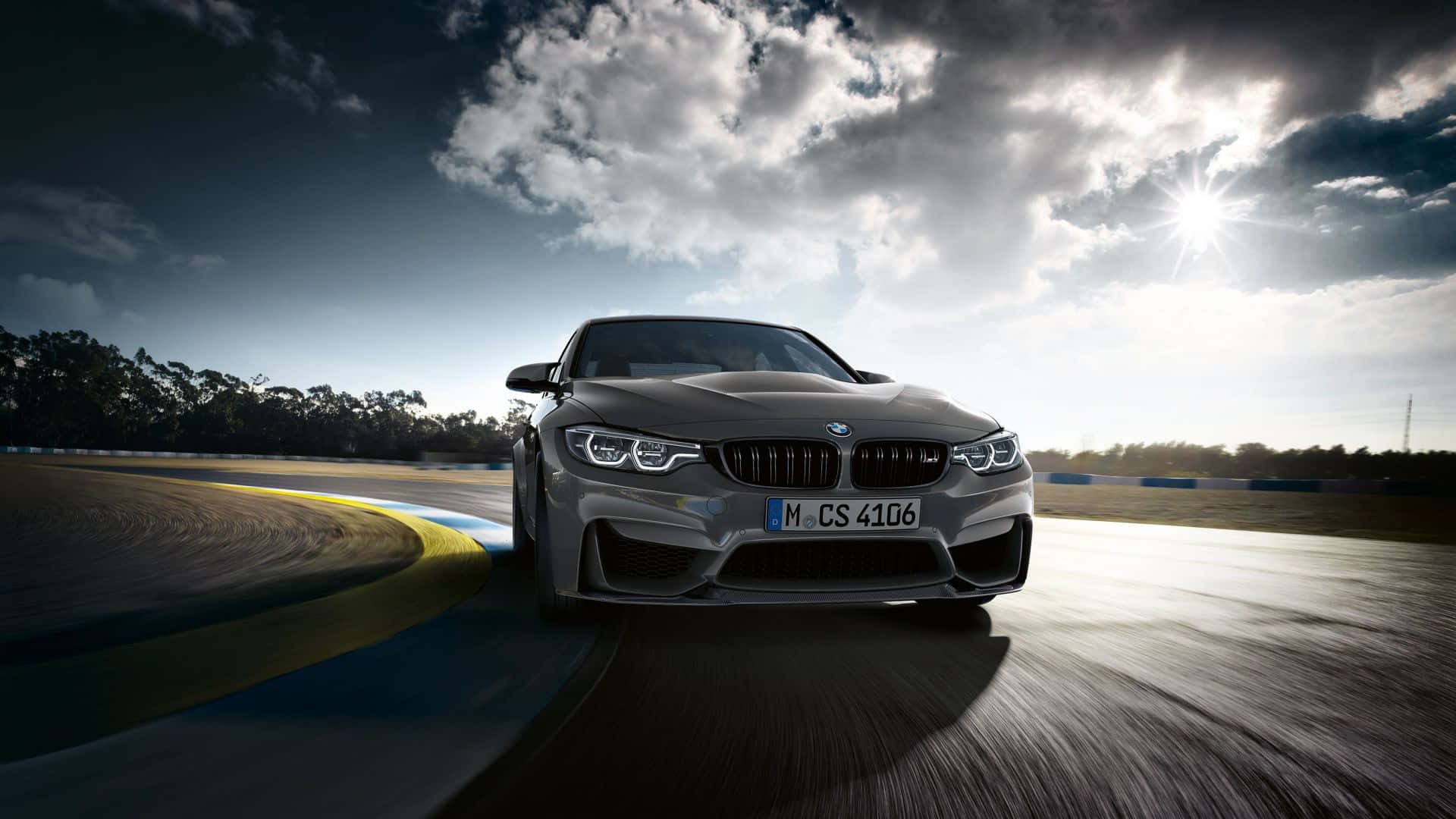 銀色BMW M4 CS在戲劇性的日落天空下在潮濕的賽道上加速行駛。