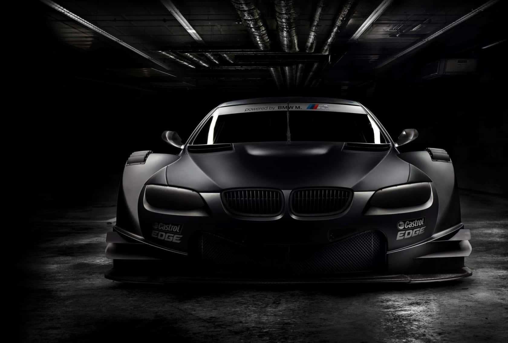 在黑暗車庫中帶有Castrol EDGE品牌的啞光黑色BMW賽車。