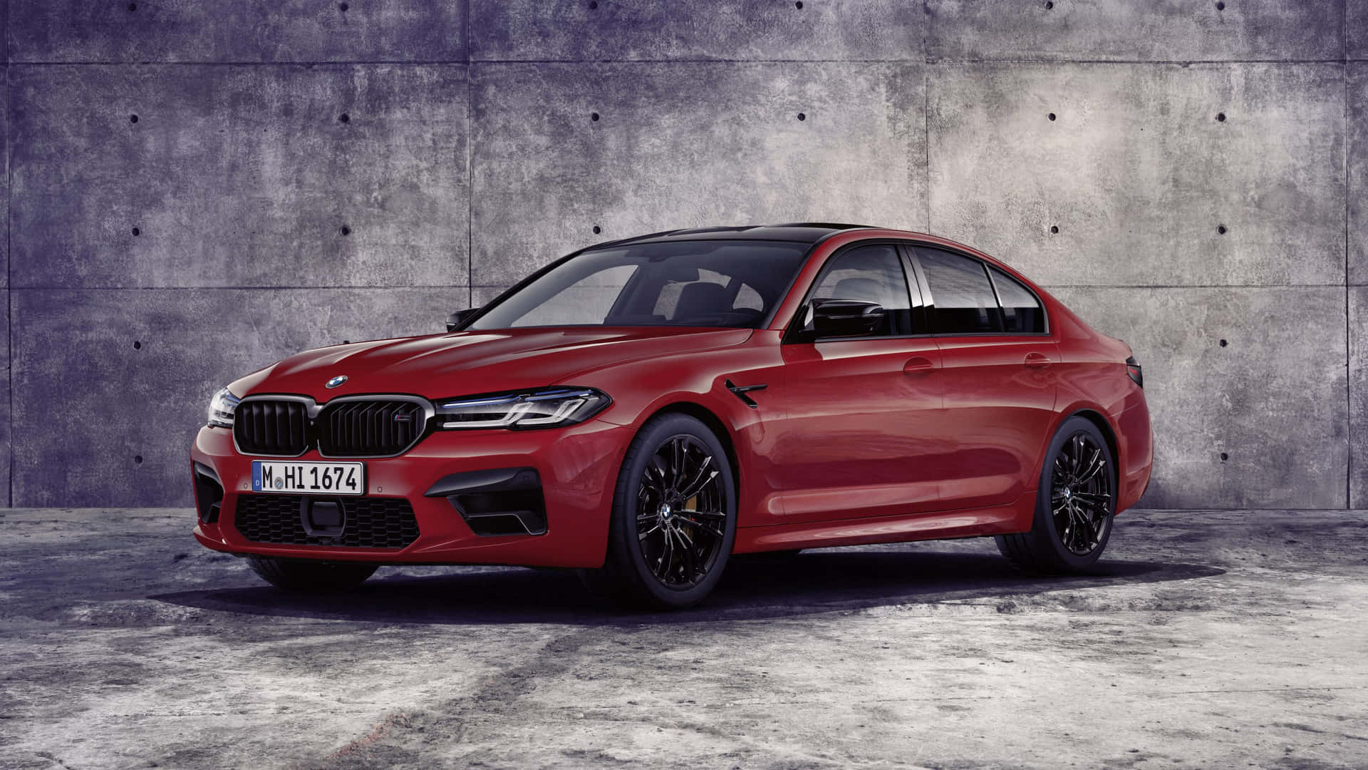 紅色BMW M5轎車停泊在灰色混凝土牆前。